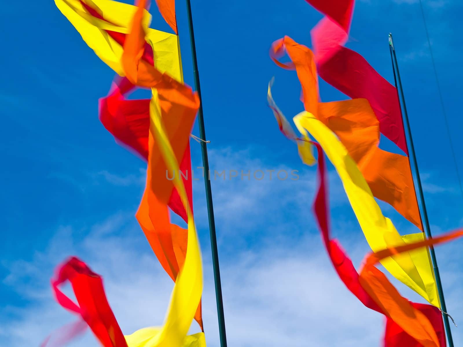 Red, Orange, and Yellow Flags Waving in a Blue Sky by Frankljunior