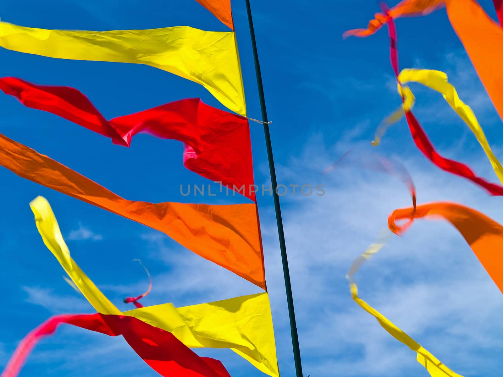 Red, Orange, and Yellow Flags Waving in a Blue Sky by Frankljunior