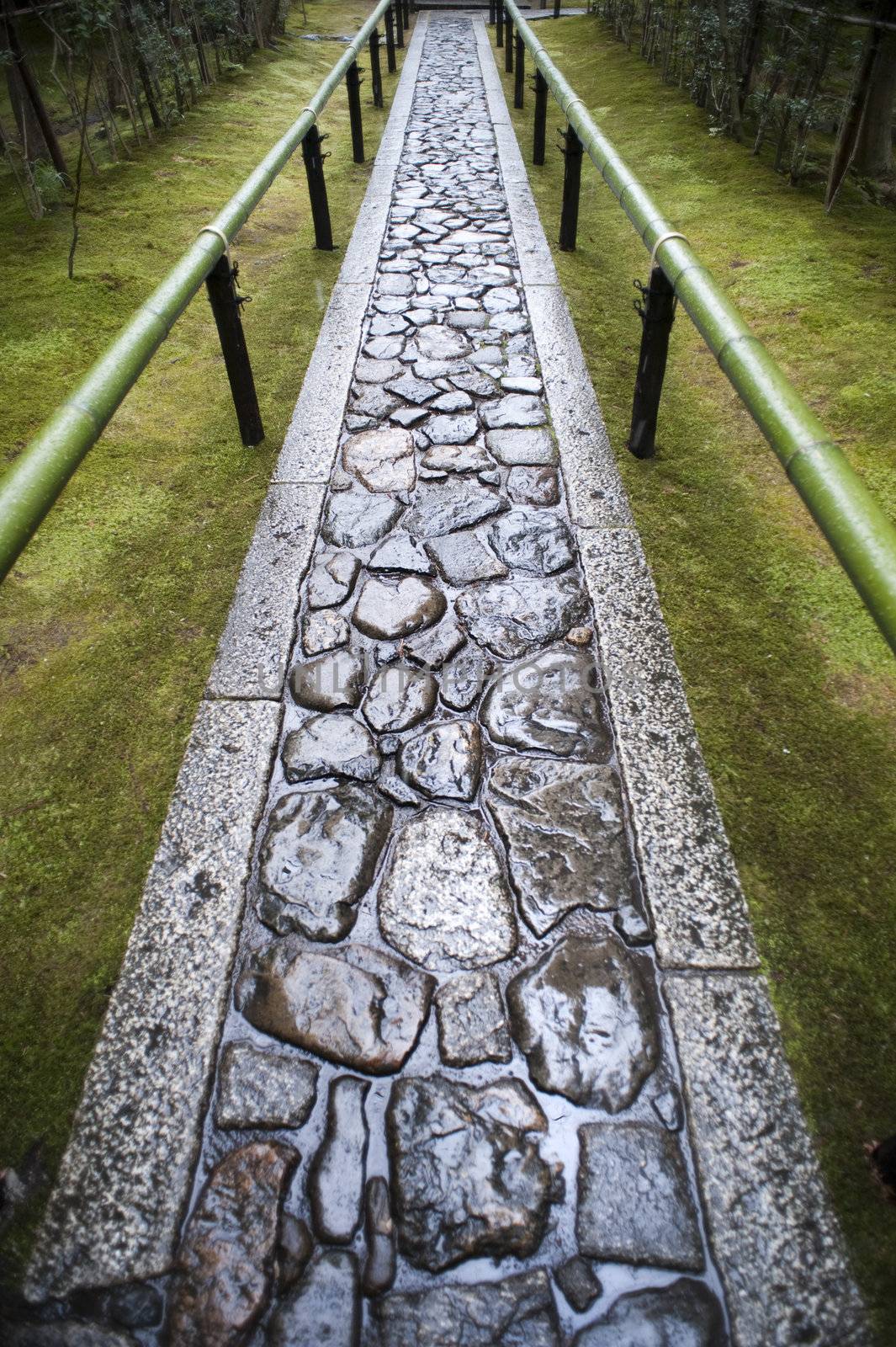 Wet paved footpath between bamboo railings in the formal garden at Koto-in, a sub temple of Daitoku-ji in Nara , Japan