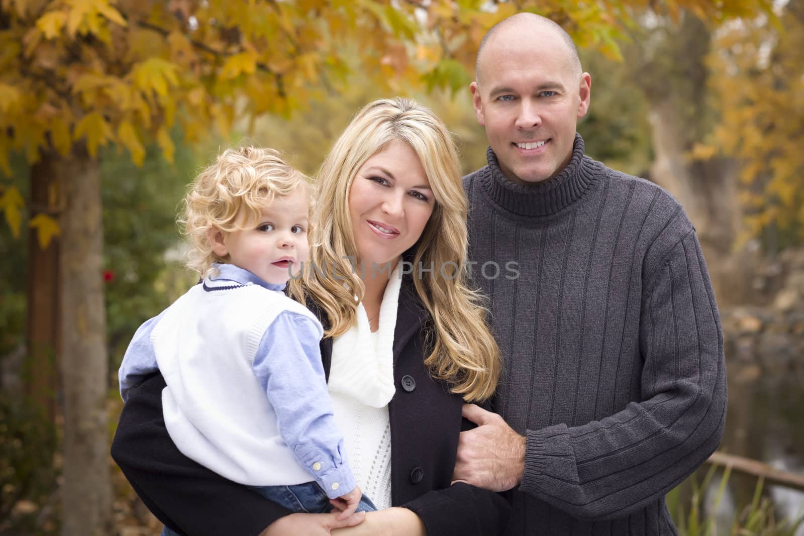 Young Attractive Parents and Child Portrait Outside in the Park.
