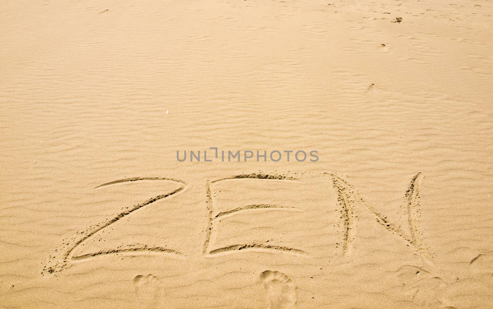 Zen Written in the Sand on a Sunny Day with Footprints