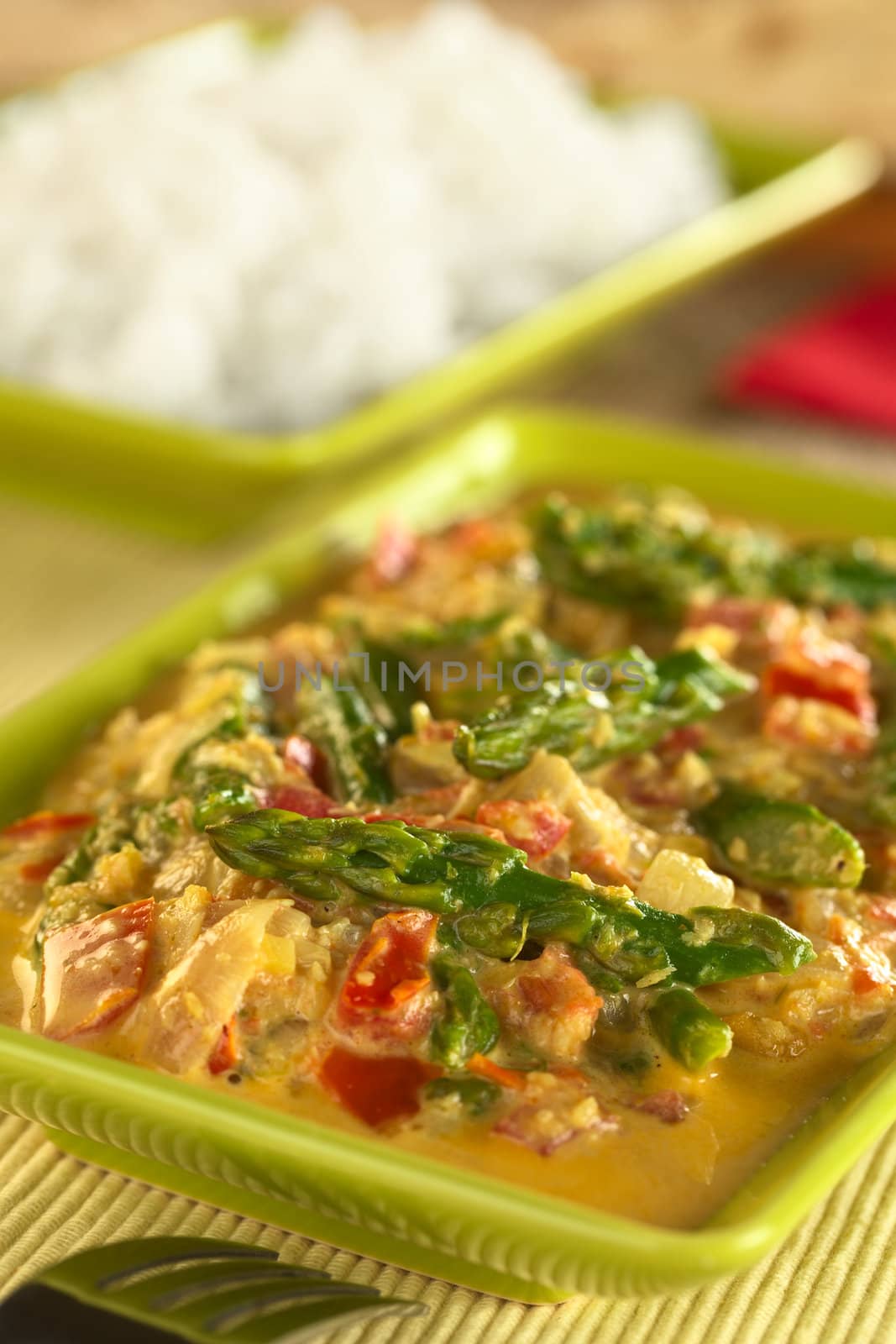 Green asparagus curry with rice in the back (Selective Focus, Focus on the asparagus head in the front)