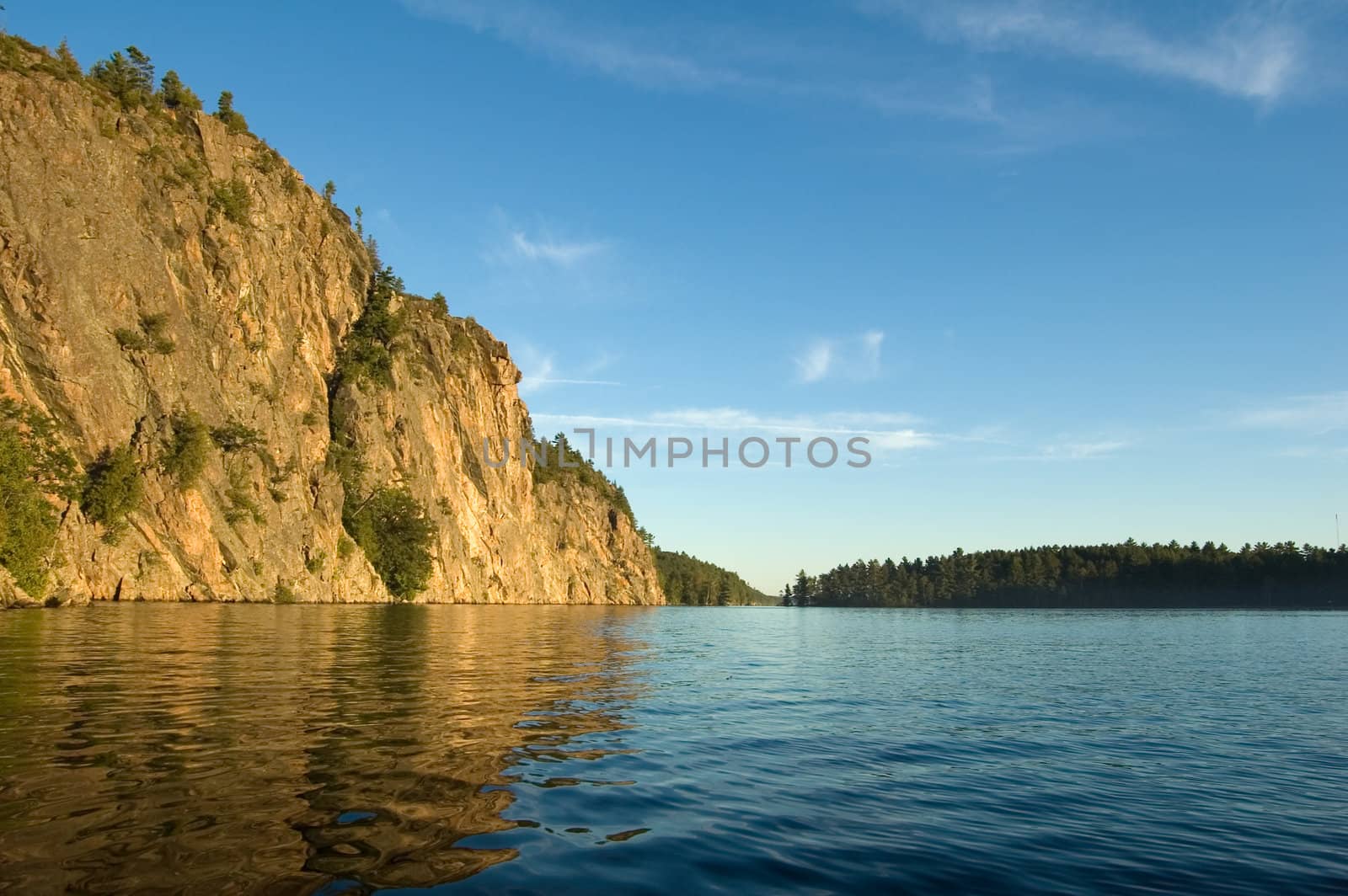 High cliff at shore of Mazinaw Lake in sunset light