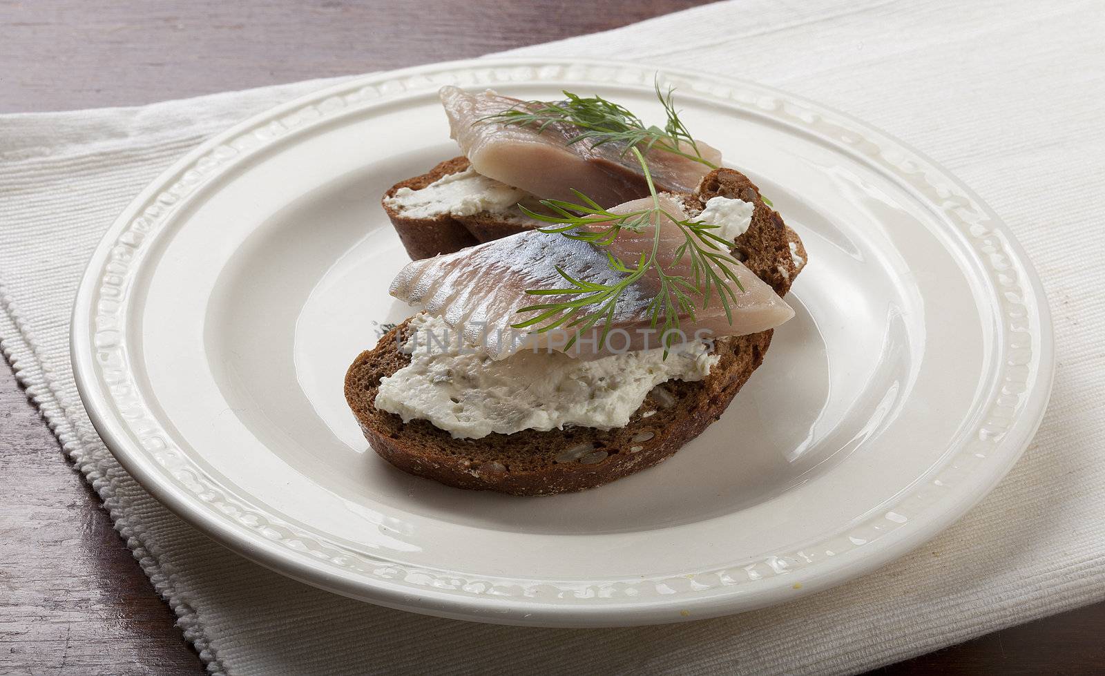 Sandwich with herring, cottage cheese and dill on the white plate