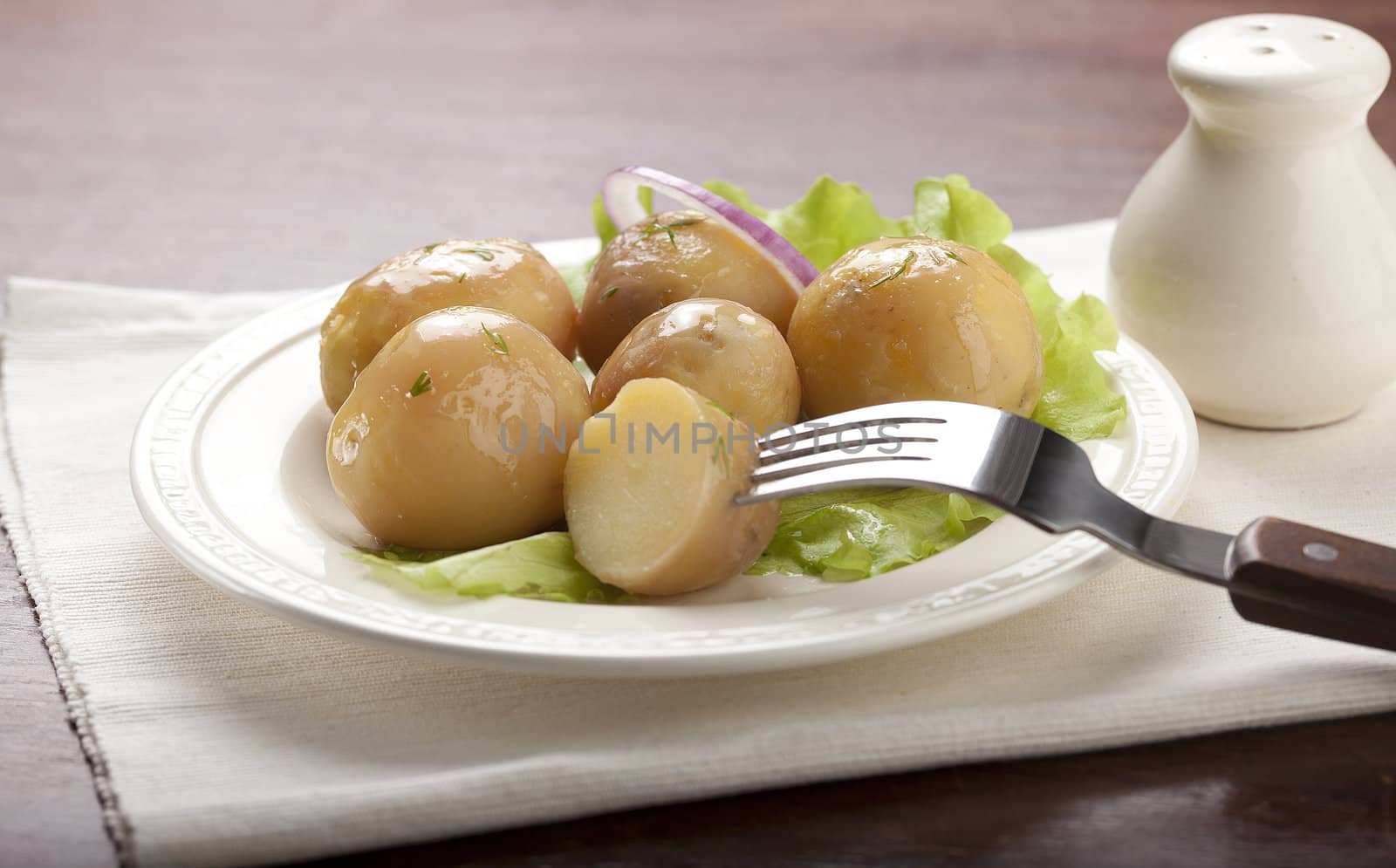 Boiled potato with onion and lettuce on the white plate