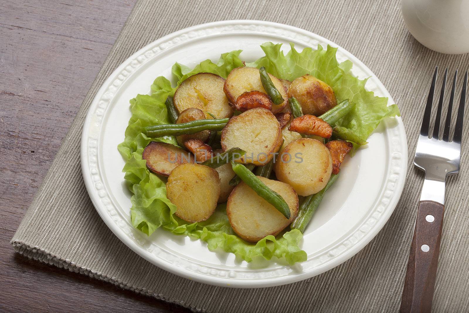 Fried potato, haricot and carrot with fresh lettuce on the white plate