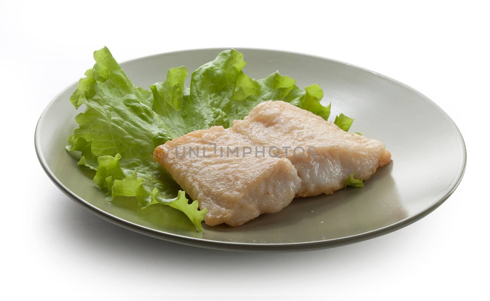 Fried fillet of pangasius with lettuce on the green plate