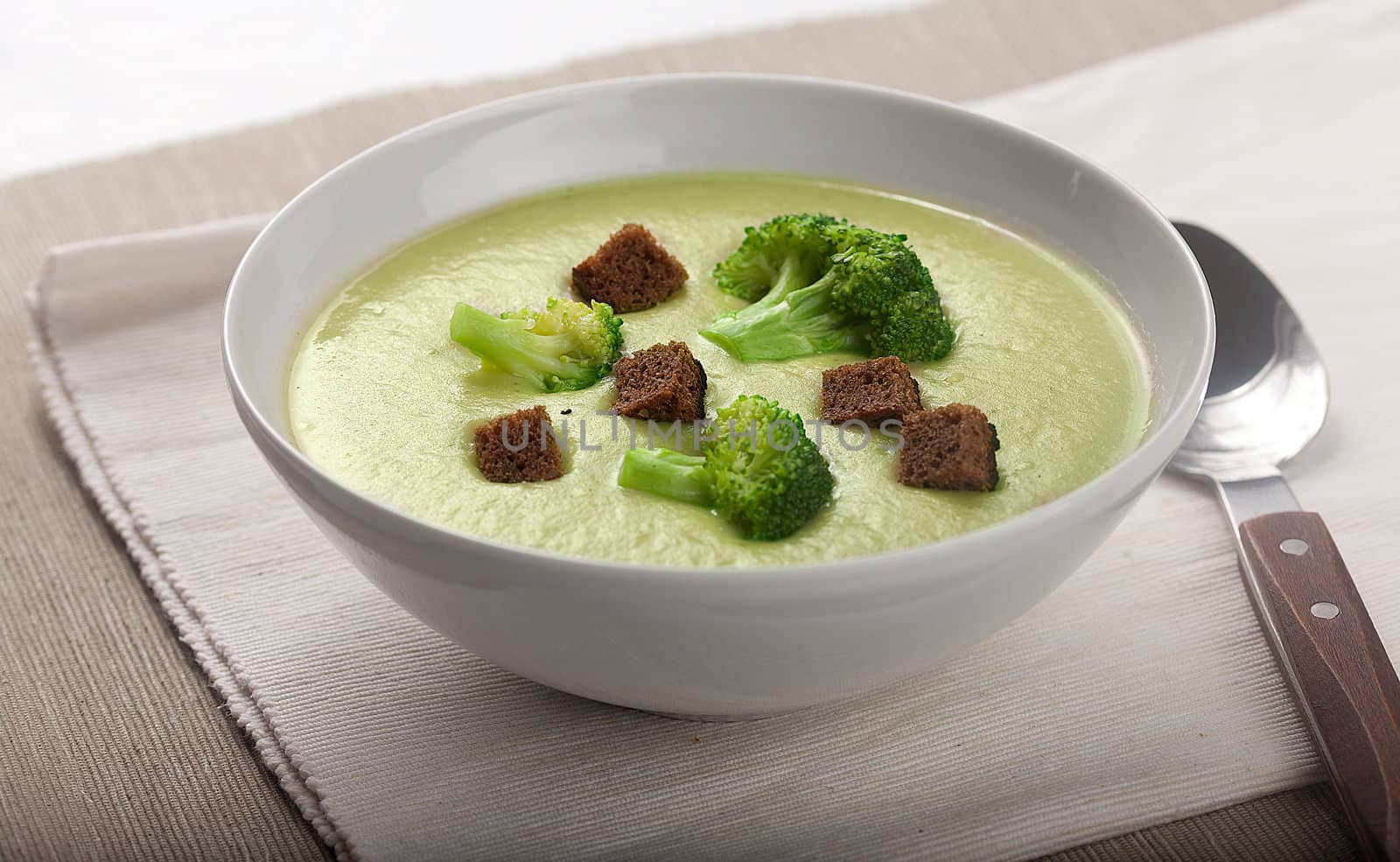 Cream soup with broccoli and dried crust in the white bowl on the napkin