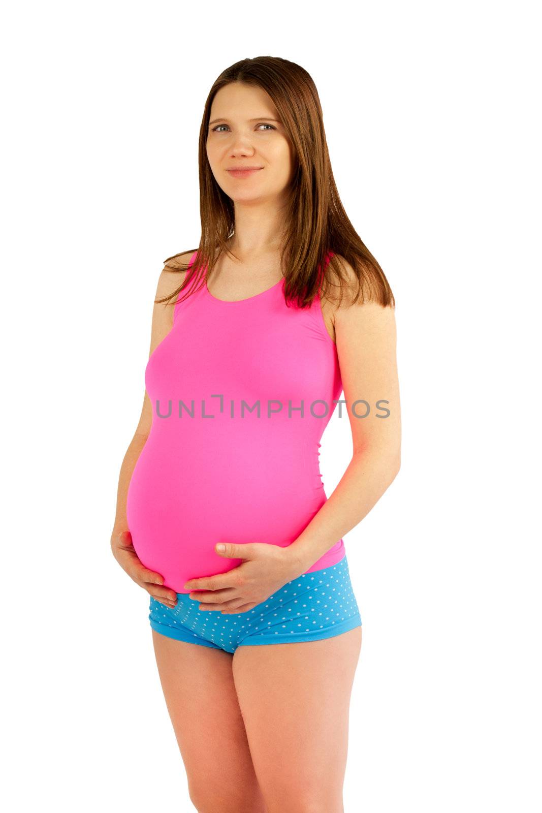 Pregnant belly. Healthy pregnant women in pink shirt and blue shorts holding her round berry with hands. White background.