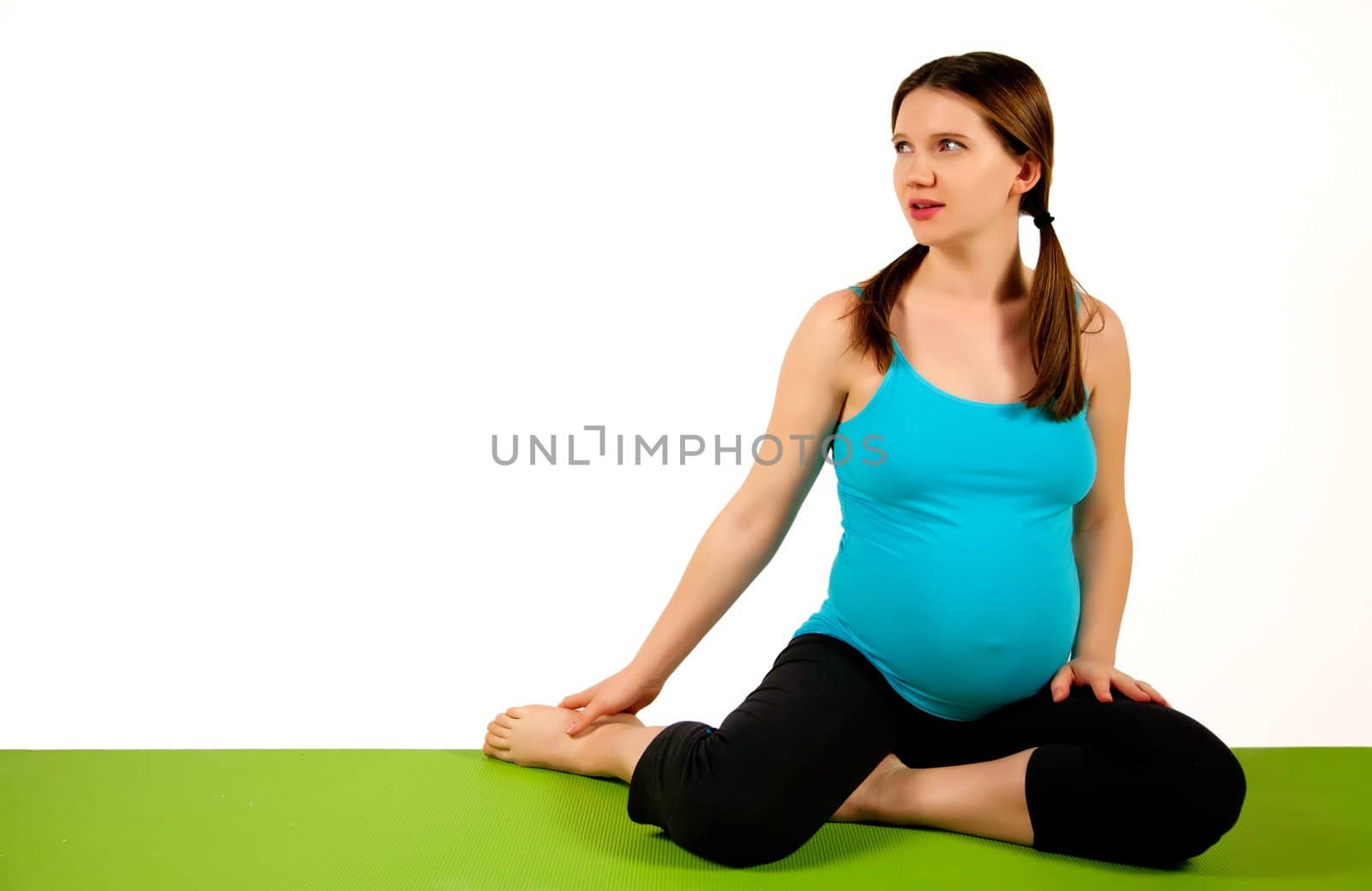 Pregnant young women stretching and exercising on the green yoga mat. 37 weeks.