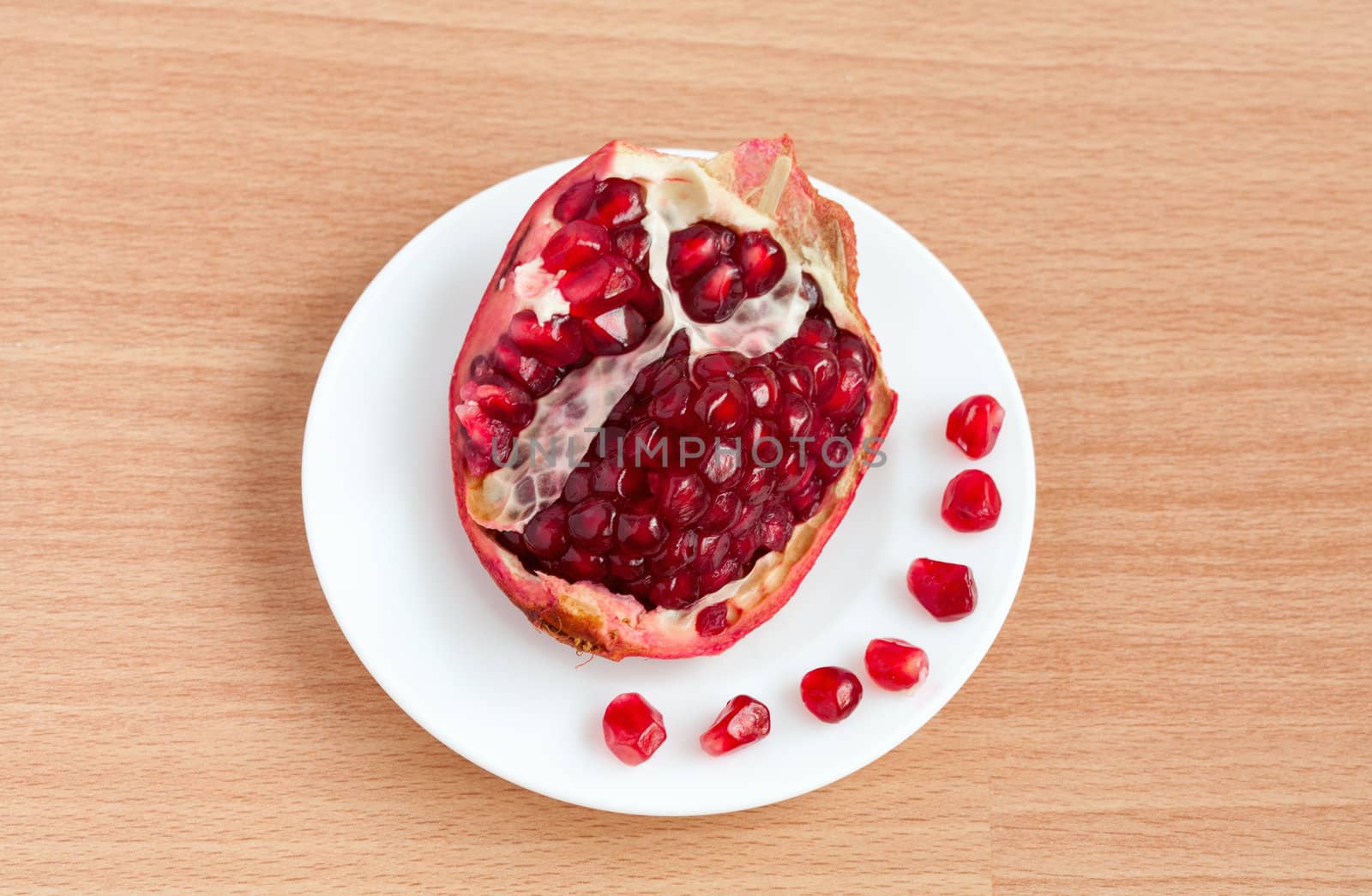 The cut pomegranate and grains on a plate by sfinks