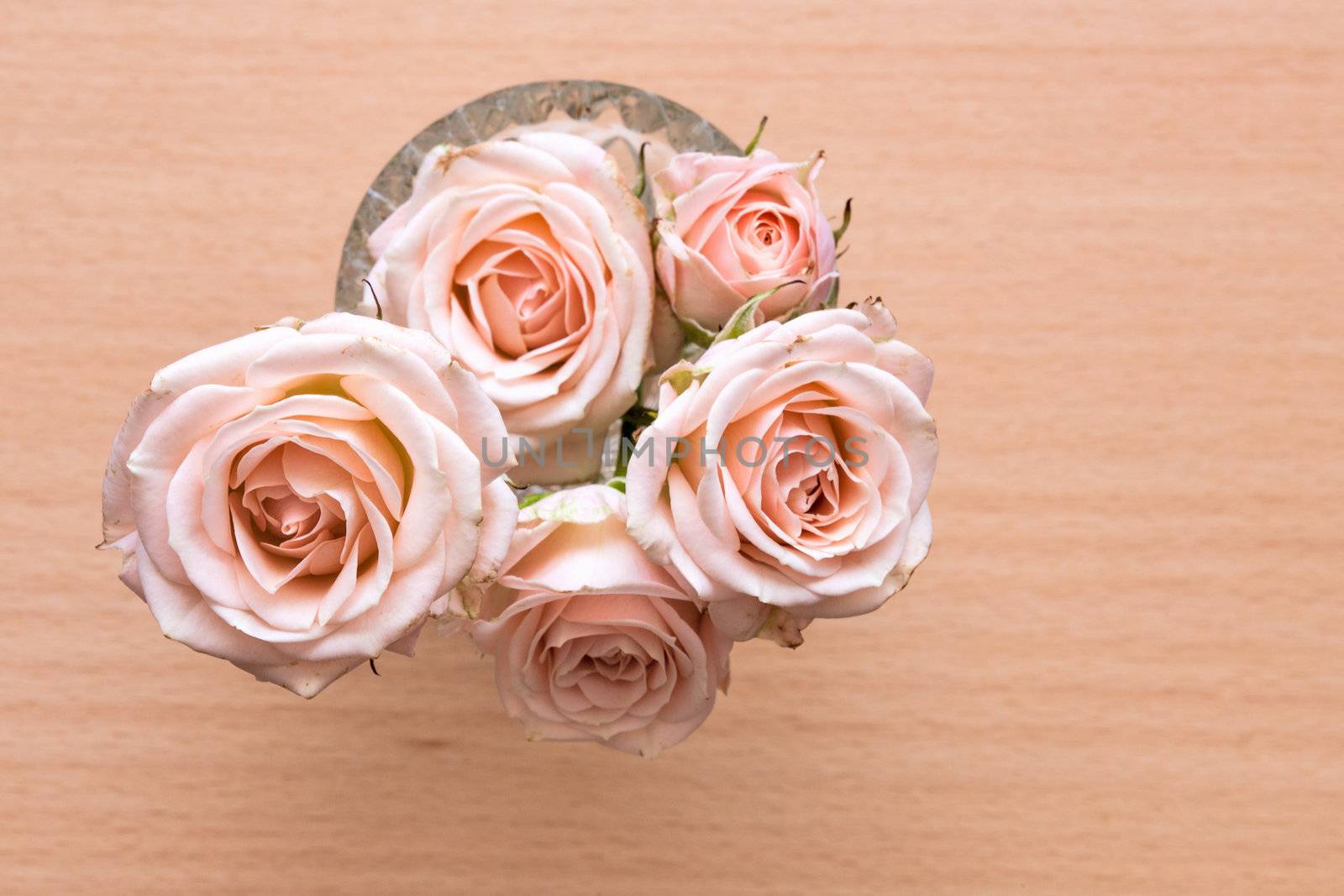 pink roses in a vase on a wooden desk