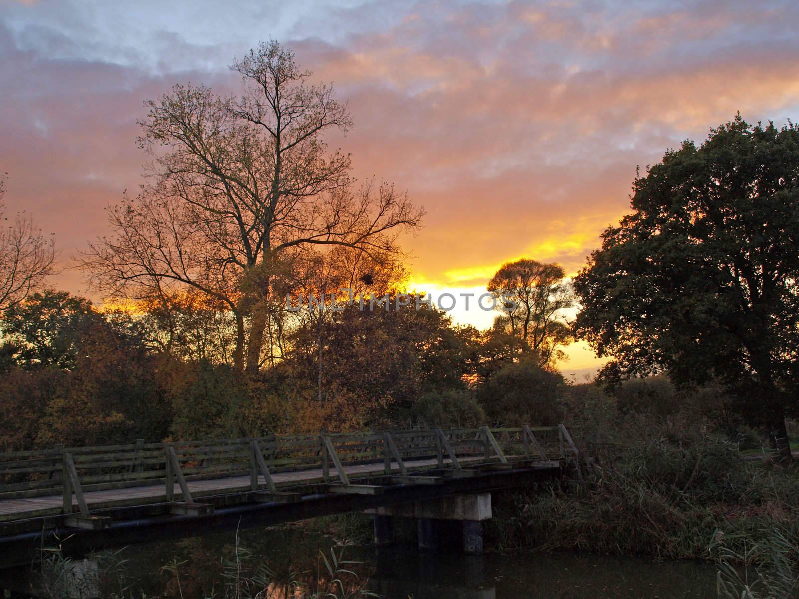 Photo taken on an autumn day at sunset of the bridge over Great Raveley Drain, at the entrance to Woodwalton fen.