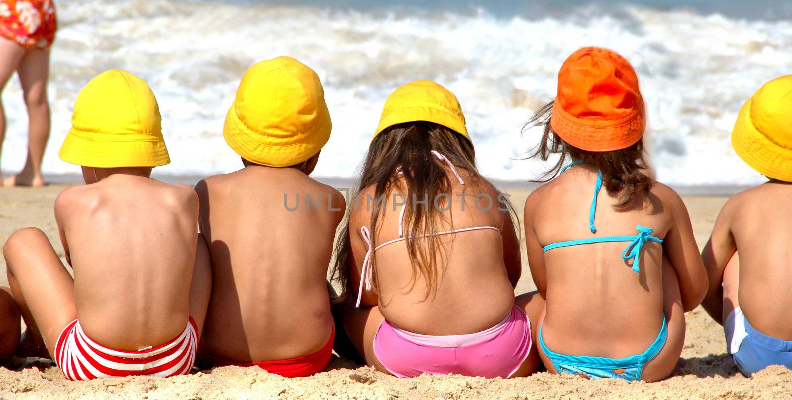 Holiday for children, funny boys and girls on the beach in vivid hats