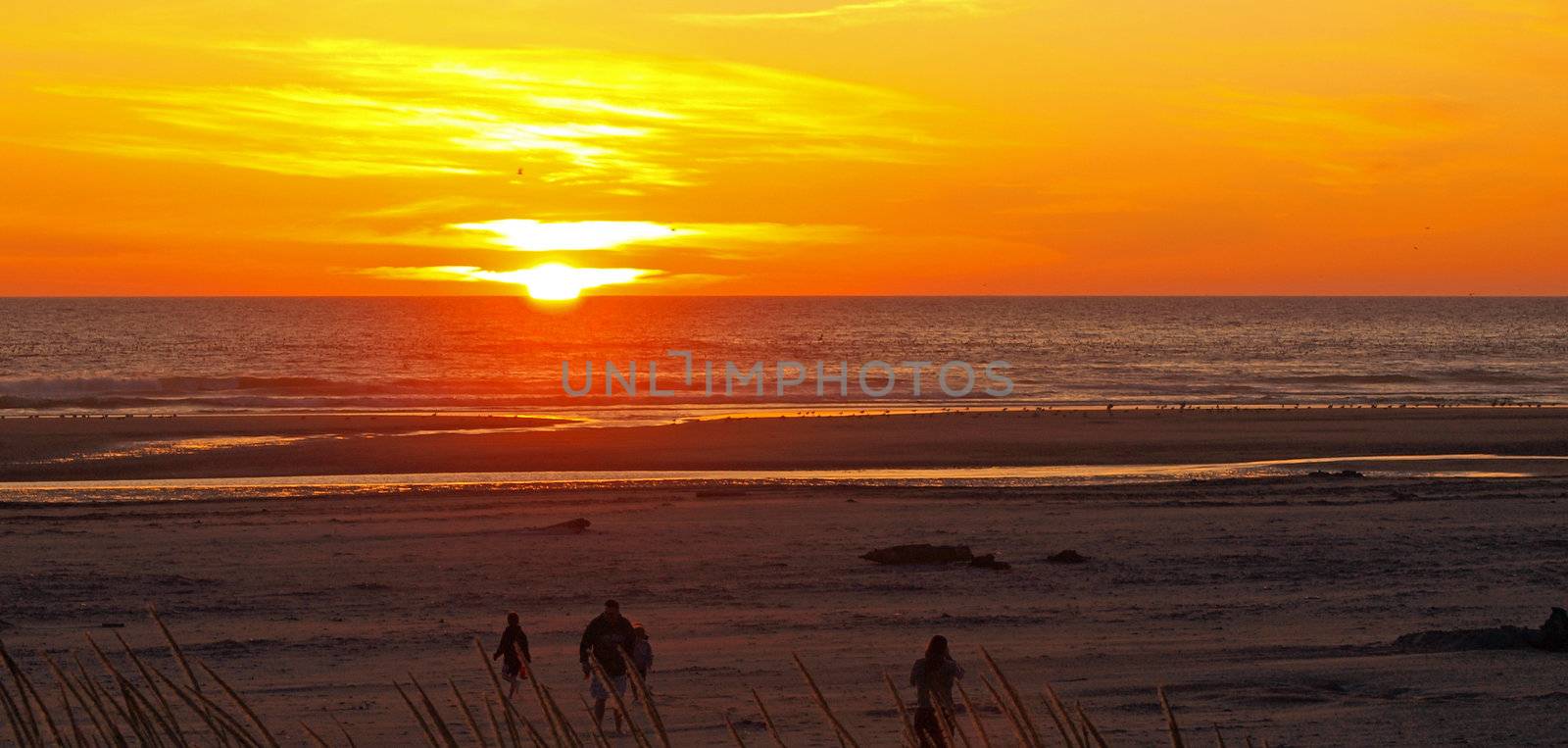 Bright Orange and Golden Sunset with a Family at the Beach