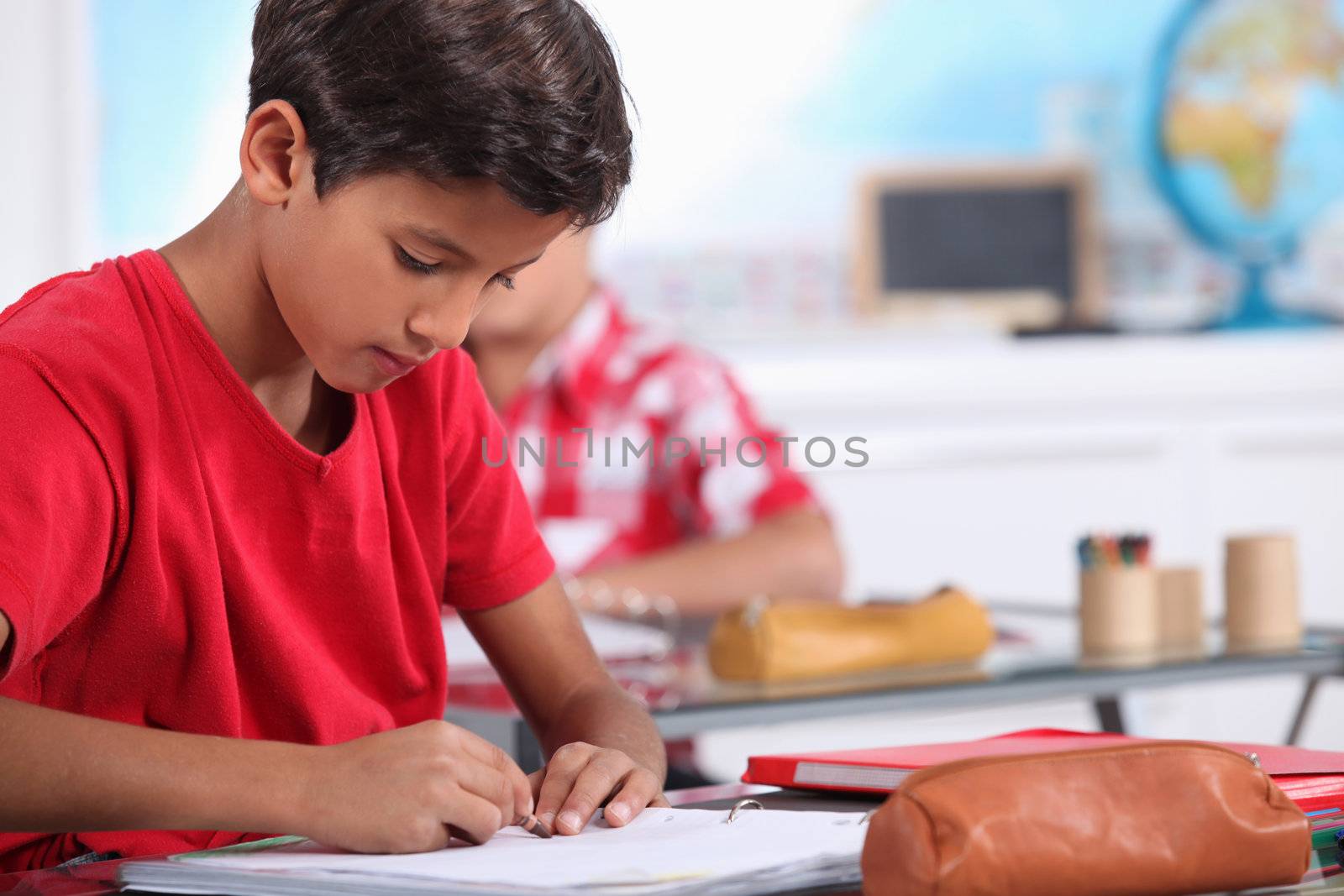 little boy focusing on his work in classroom by phovoir