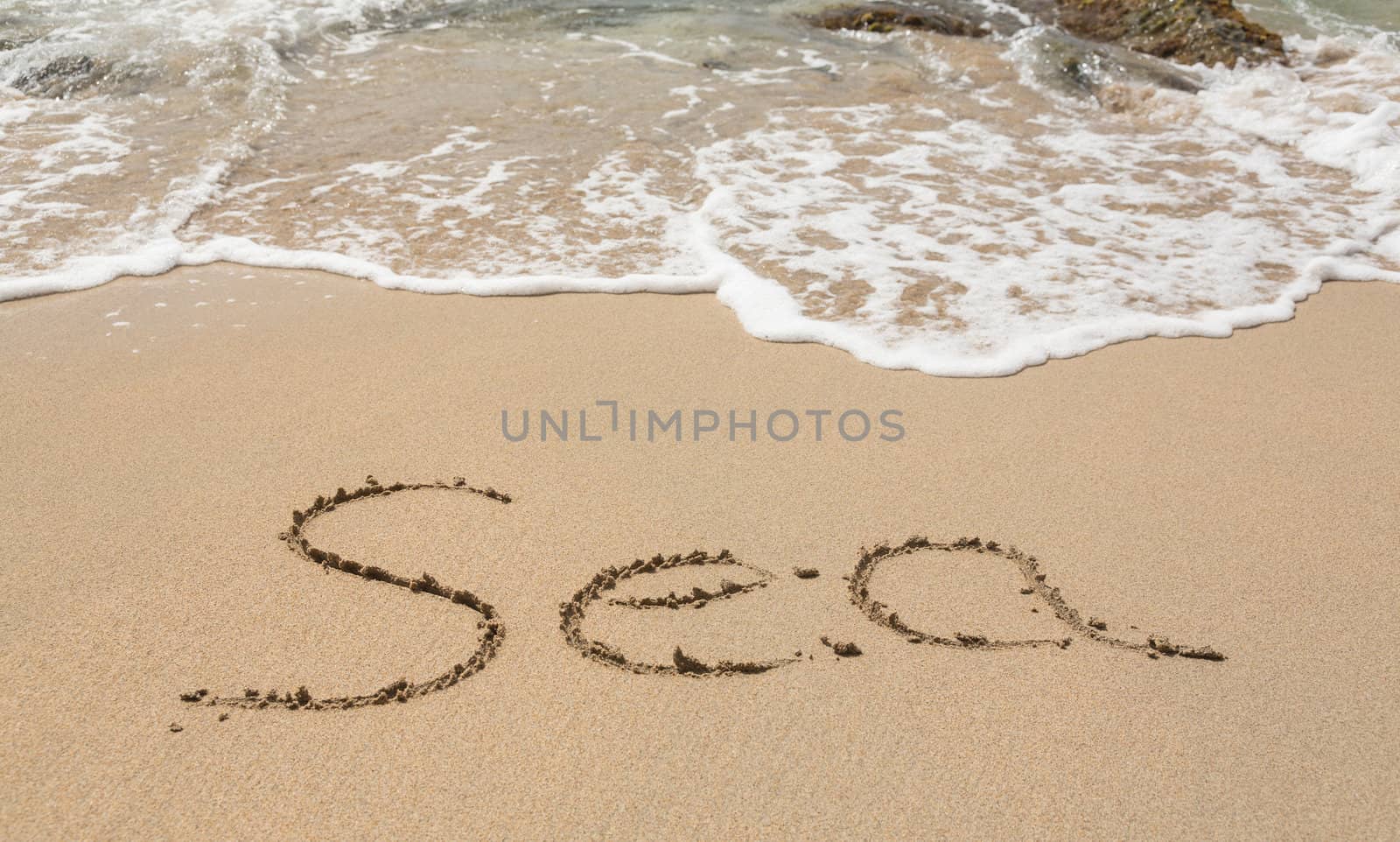 Sand drawing on warm beach by ocean surf in Caribbean spelling Sea