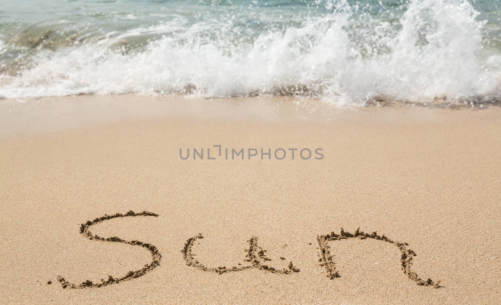 Sand drawing on warm beach by ocean surf in Caribbean spelling Sun