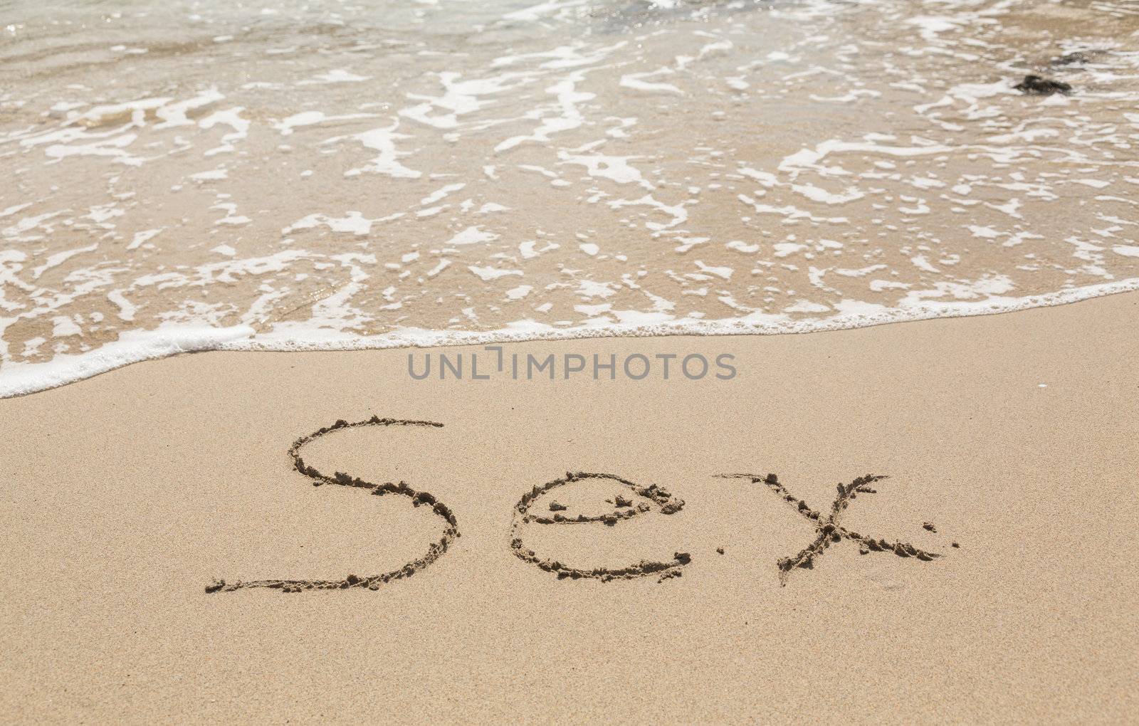 Sand drawing on warm beach by ocean surf in Caribbean spelling Sex