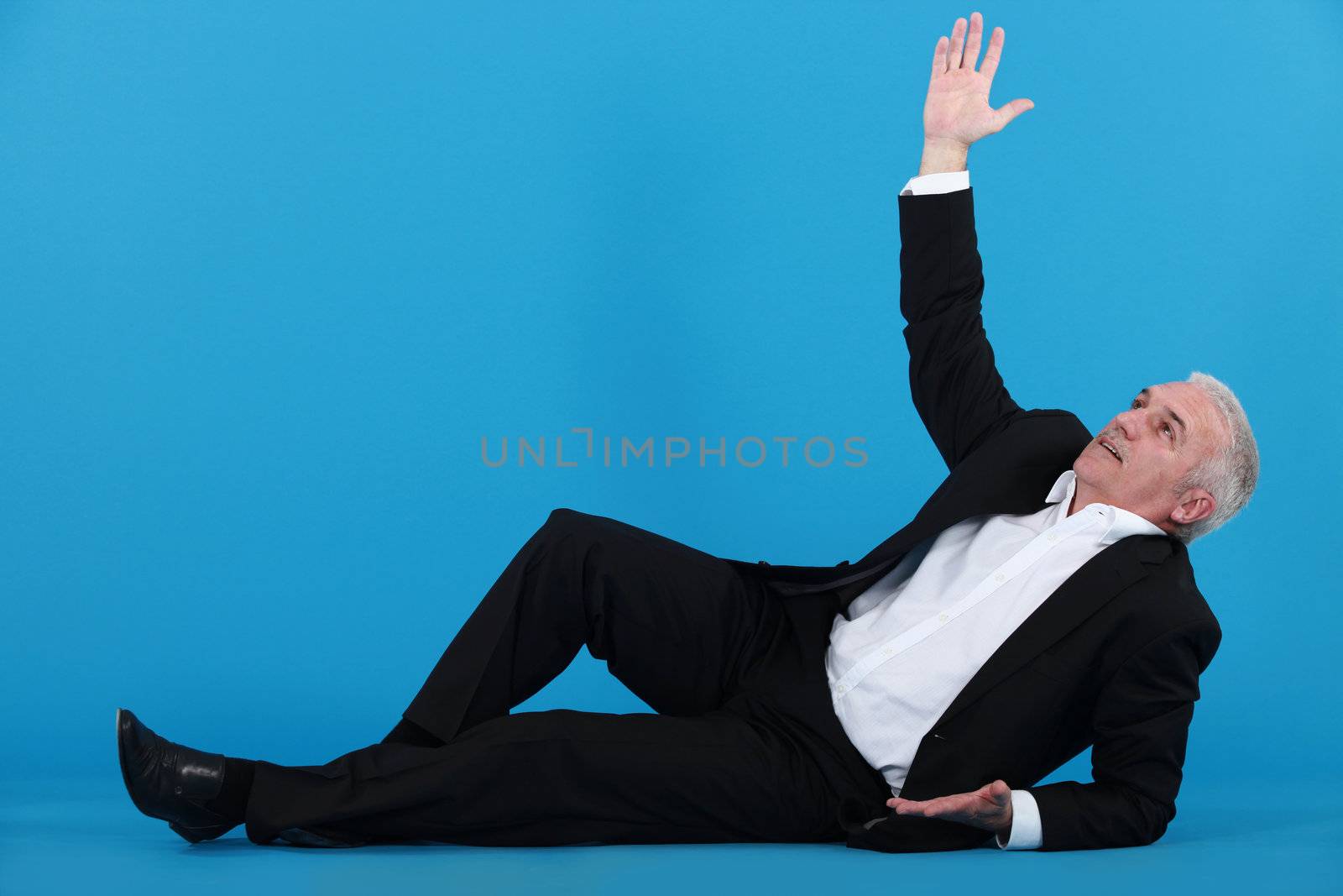 A mature businessman lying on the floor.