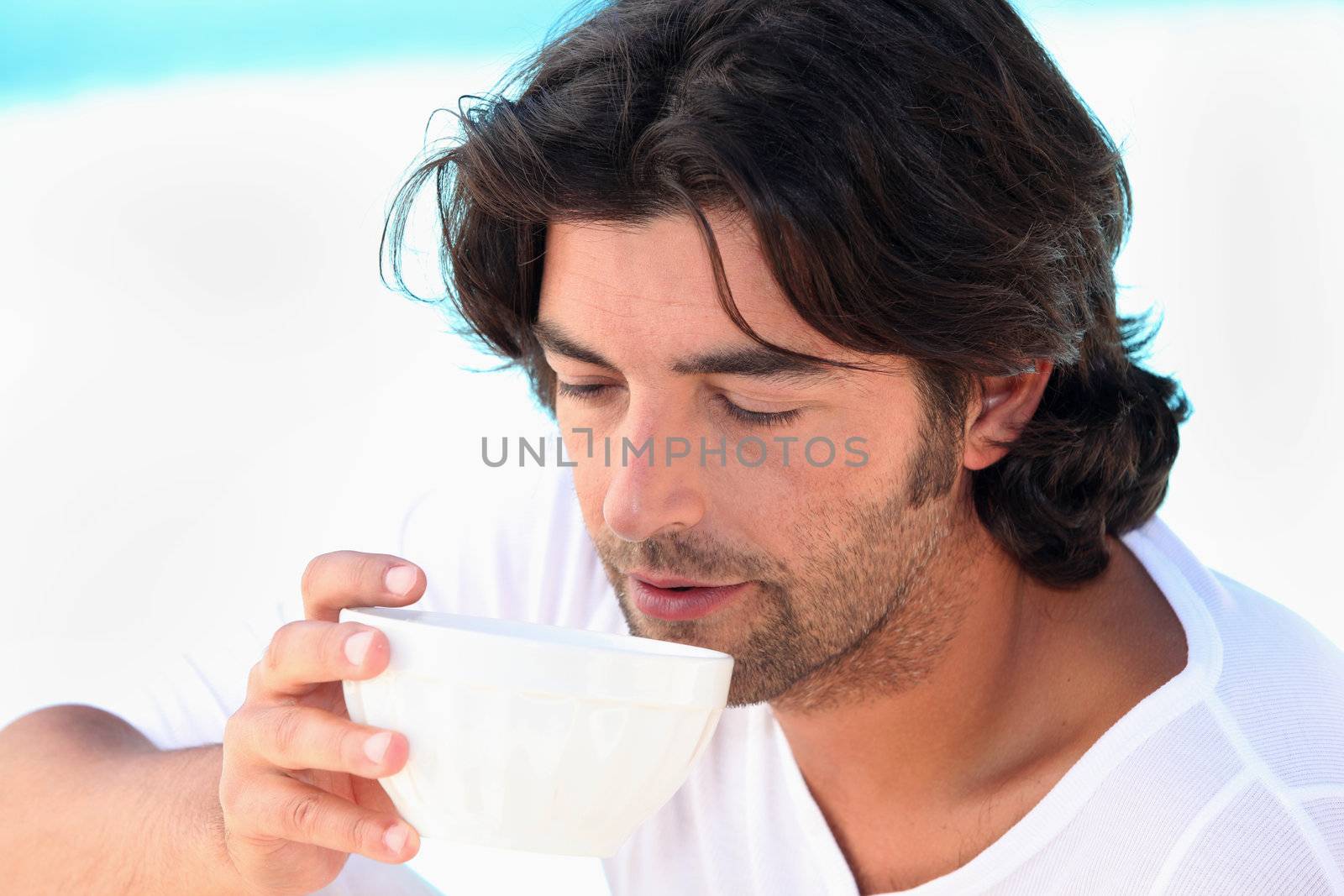 Man drinking coffee by swimming pool