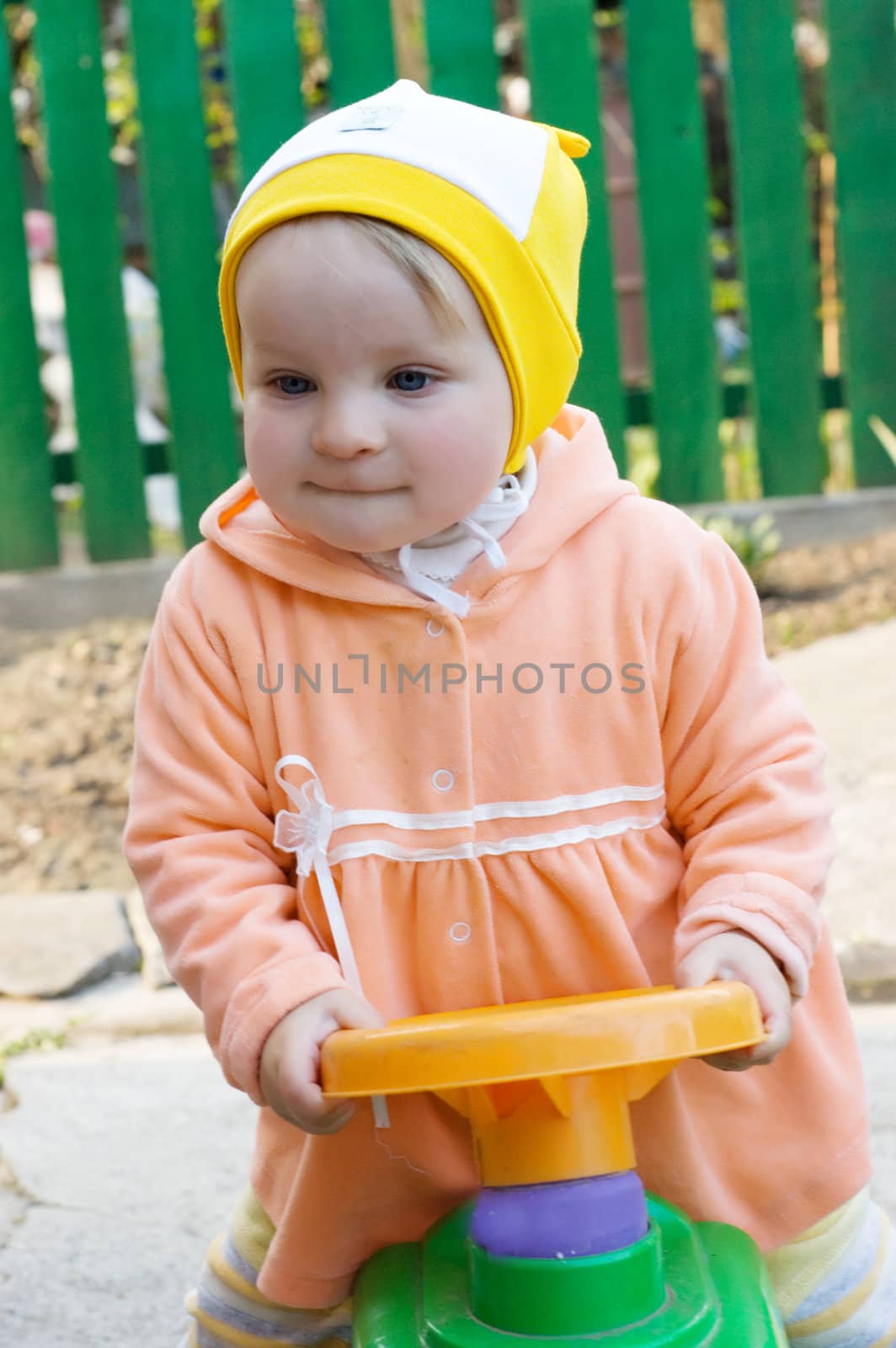 Baby girl on the car toy in yard