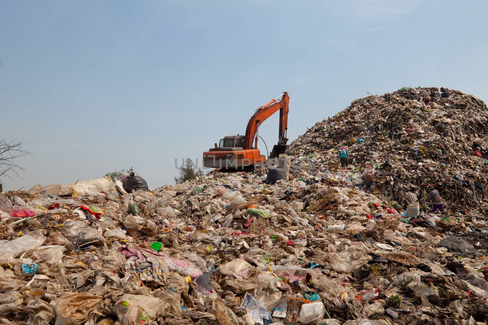 Backhoe moves trash in a landfill site, pollution, Global warming