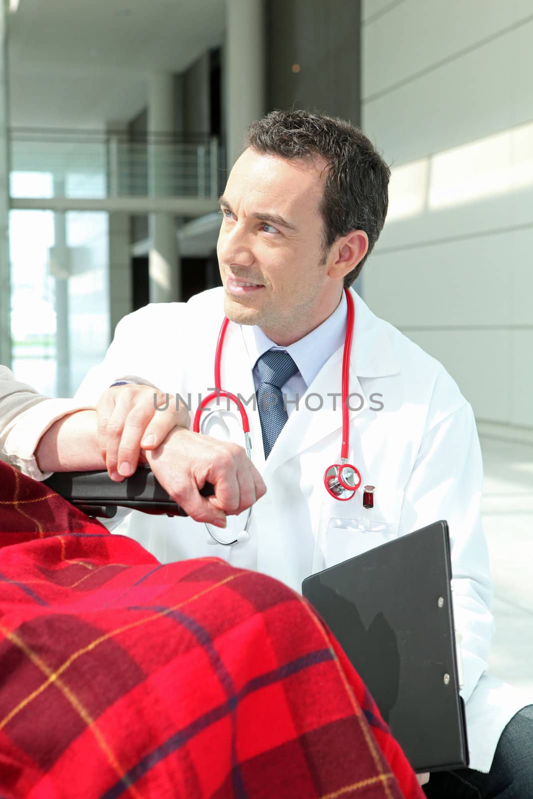 Doctor talking to a woman in a wheelchair by phovoir