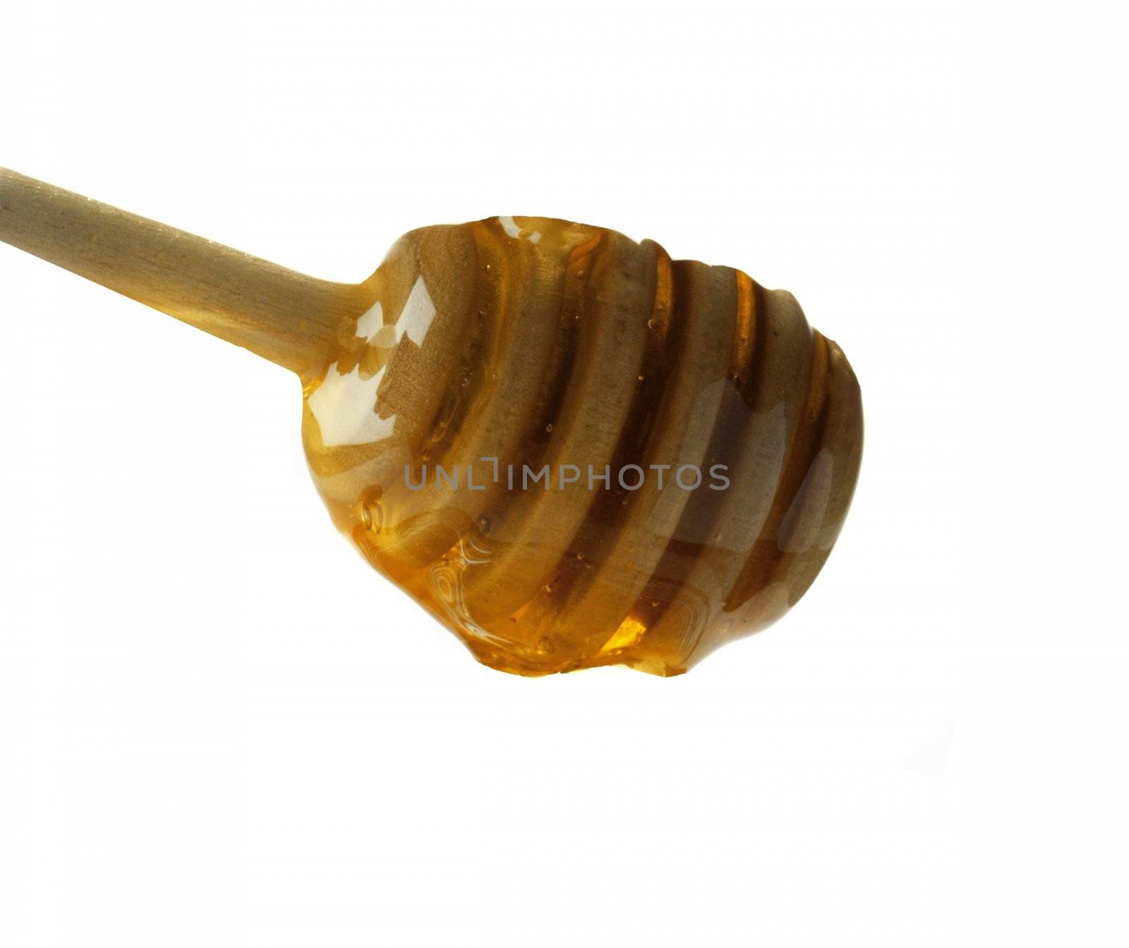 Honey dripping from a wooden dipper isolated