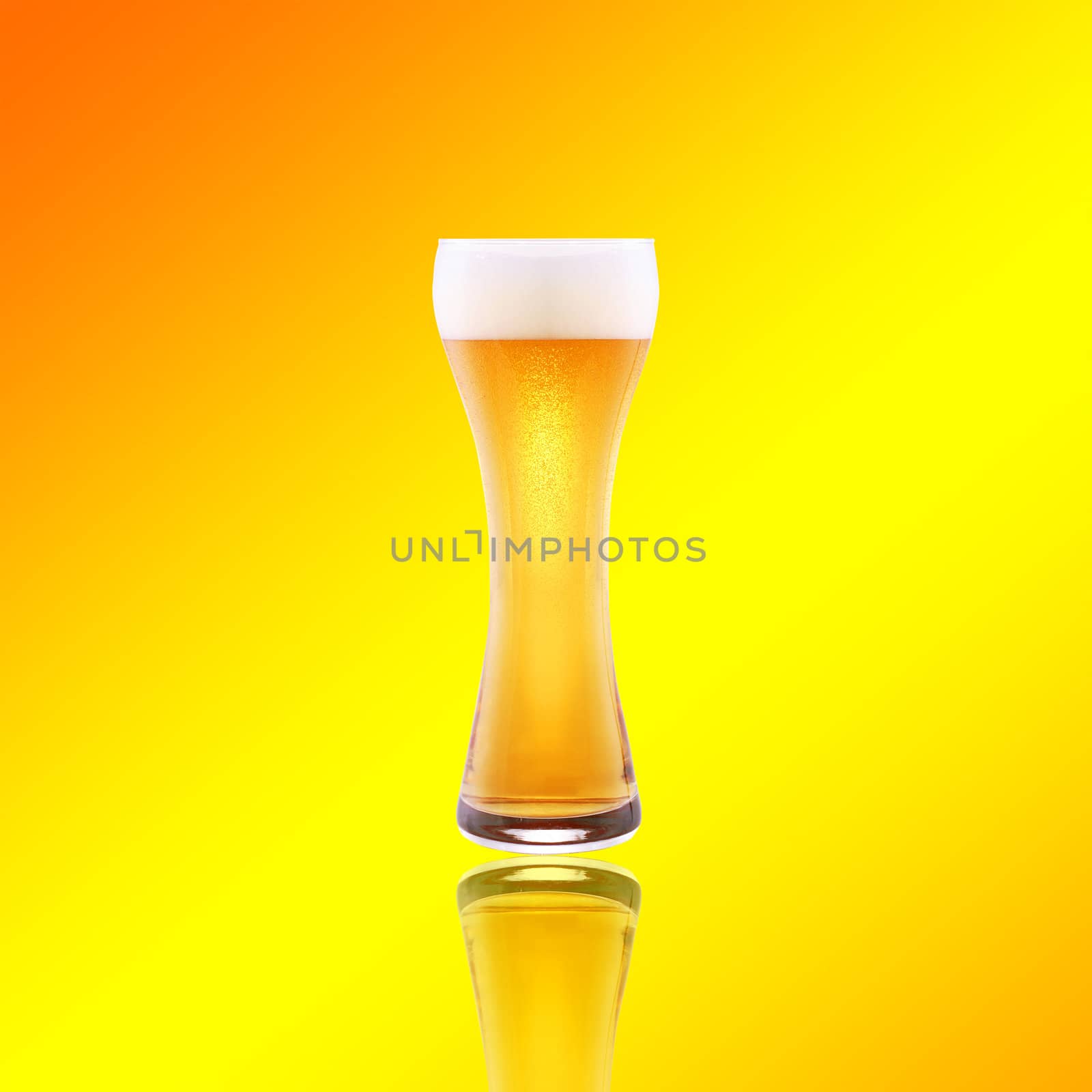 Beer glass with froth over yellow background
