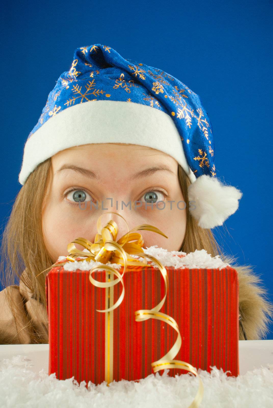 Surprised teen girl looking from behind the Christmas present by AndreyKr