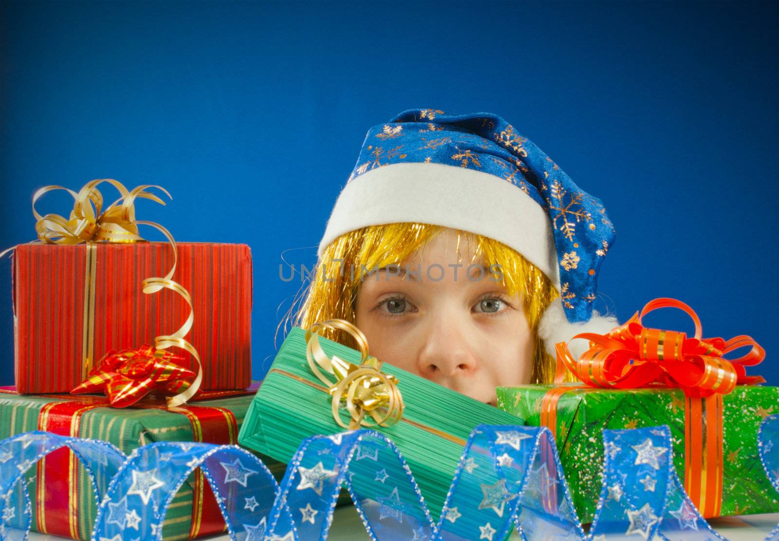 Surprised teen girl looking from behind the Christmas presents by AndreyKr
