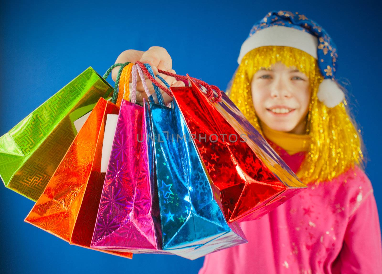 Teen girl holds a variety of colorful bags against blue background