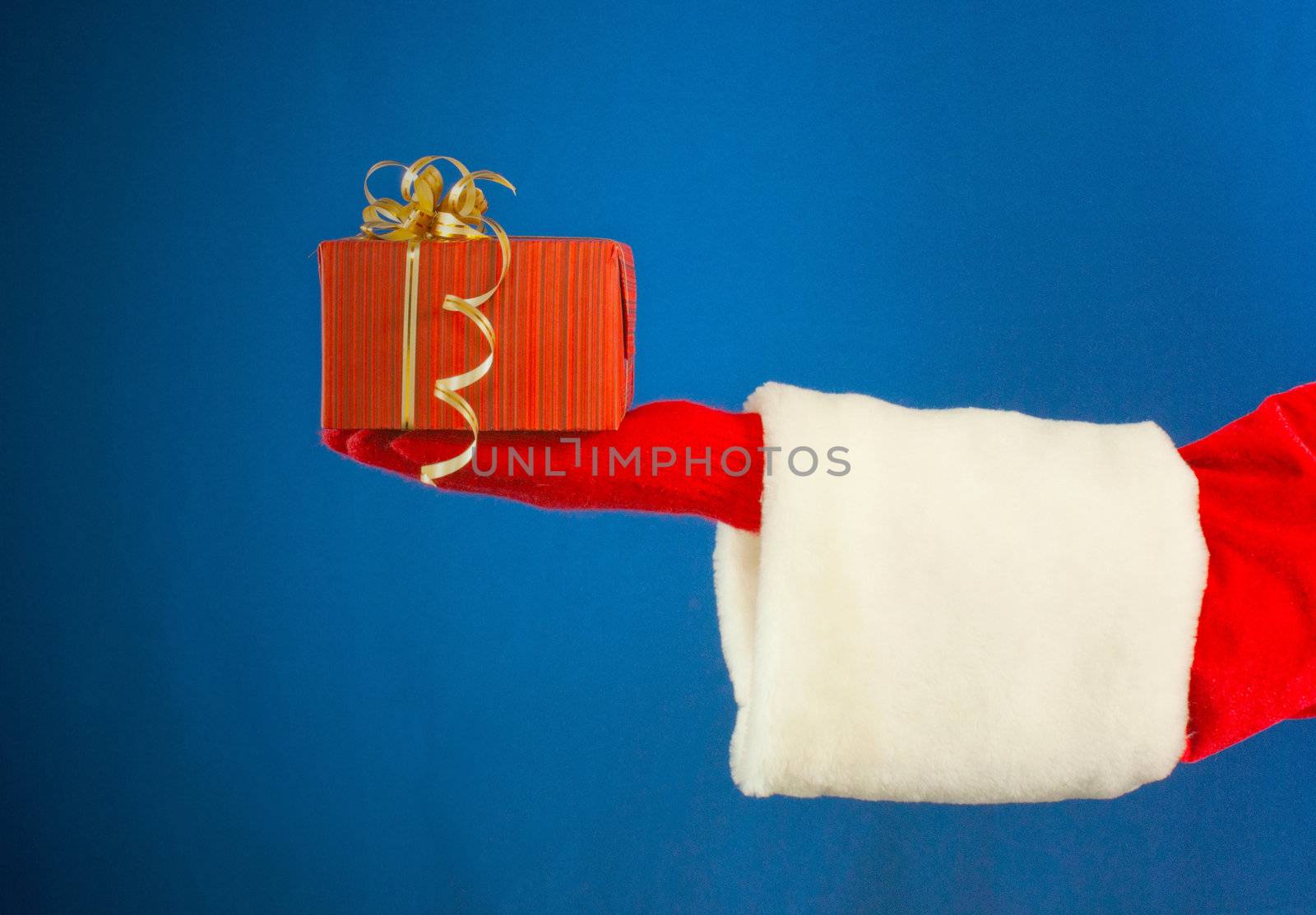 Santa's hand holding a present over blue background