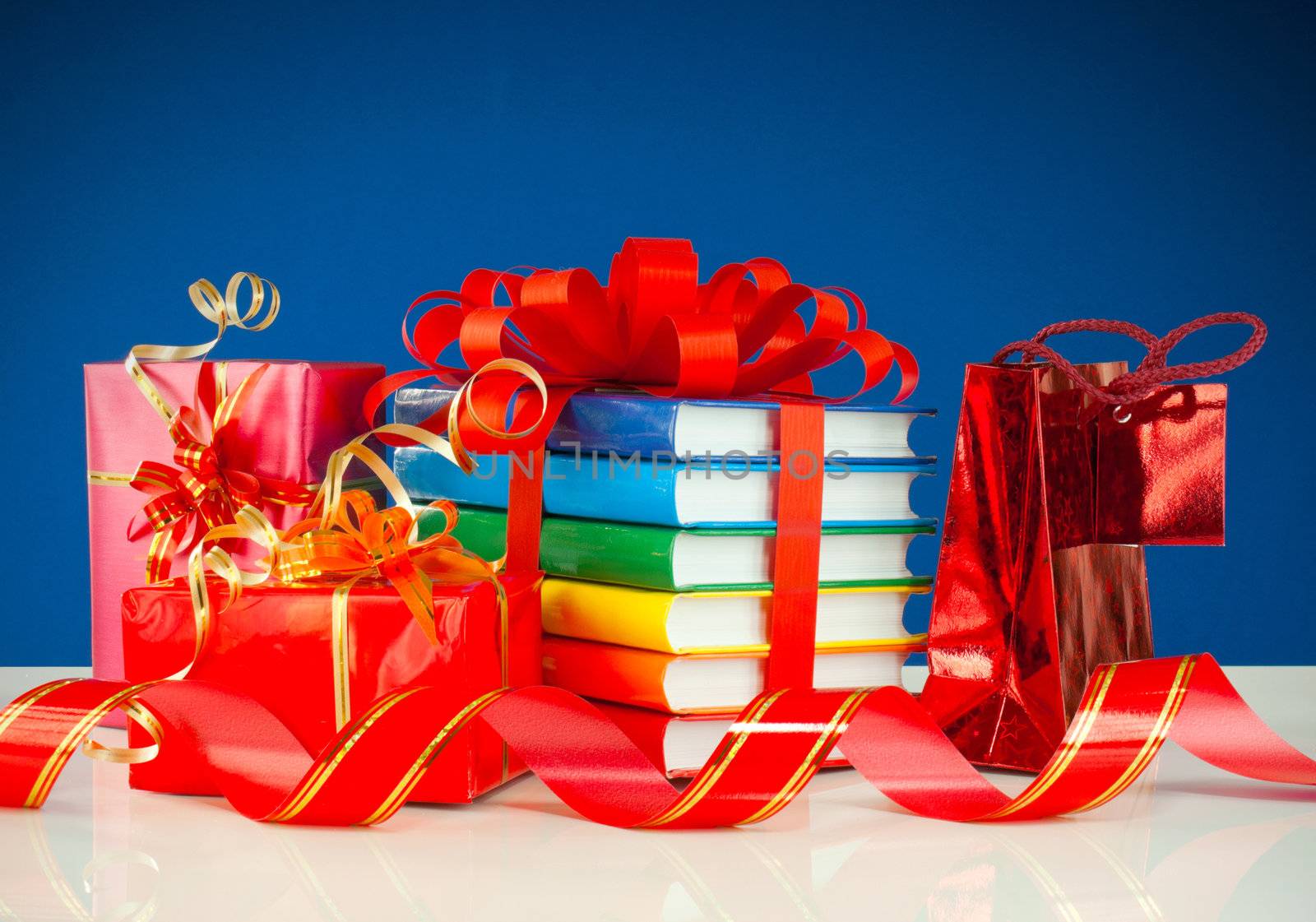 Christmas presents with stack of books against blue background