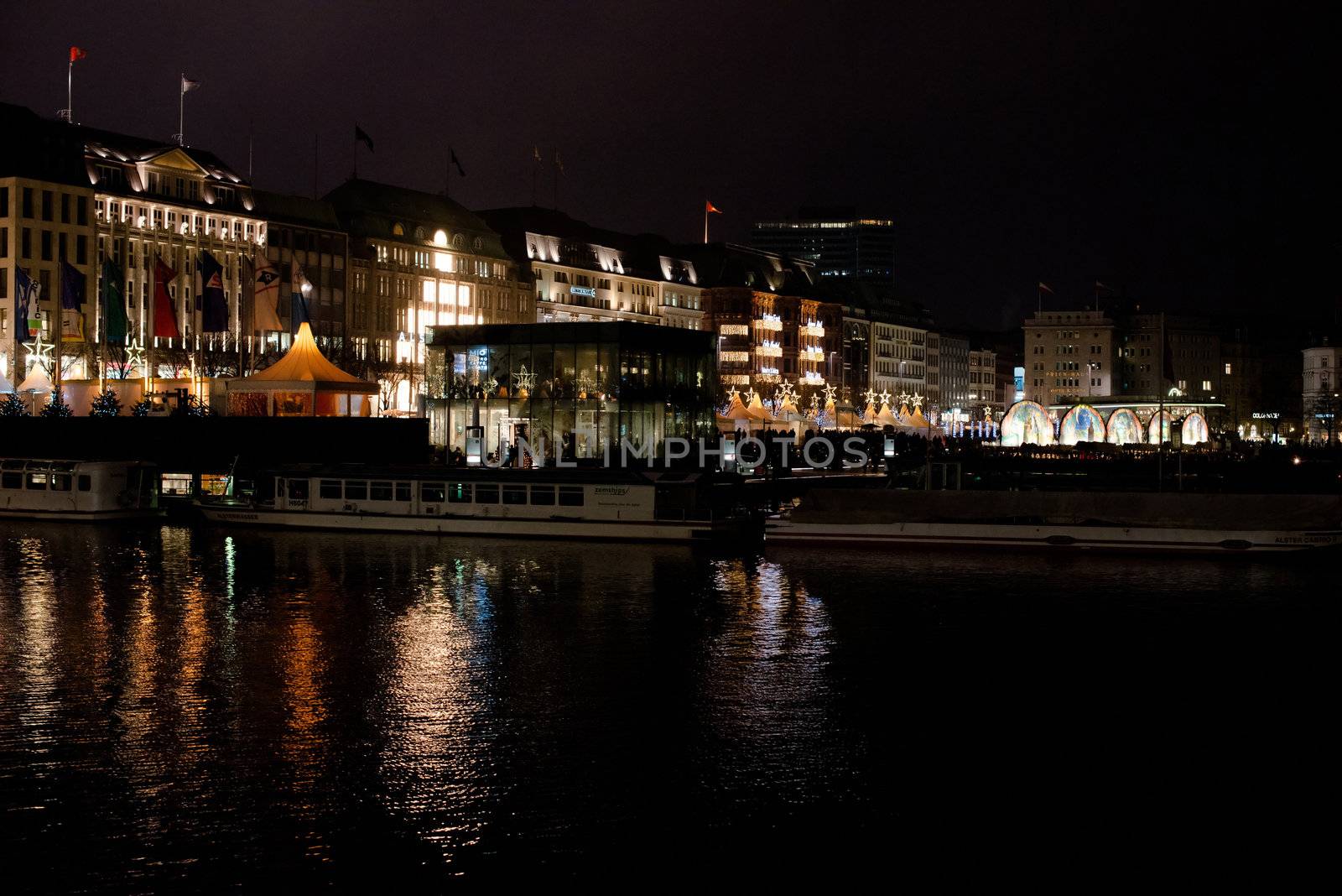 HAMBURG - DECEMBER 1, 2012: People visit traditional Christmas market around Alster river in Hamburg, Germany on December 1, 2012. The famous Hamburg Christmas market is located around the town hall and is a popular tourist attraction due to its gorgeous decorated stands.