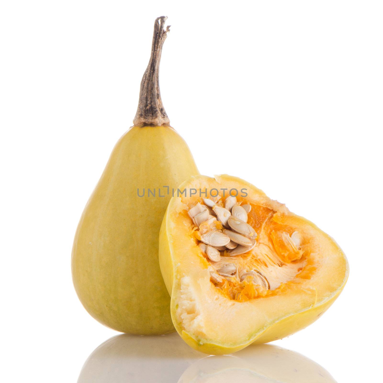 Closeup detail of yellow pumpkin on white reflective background.