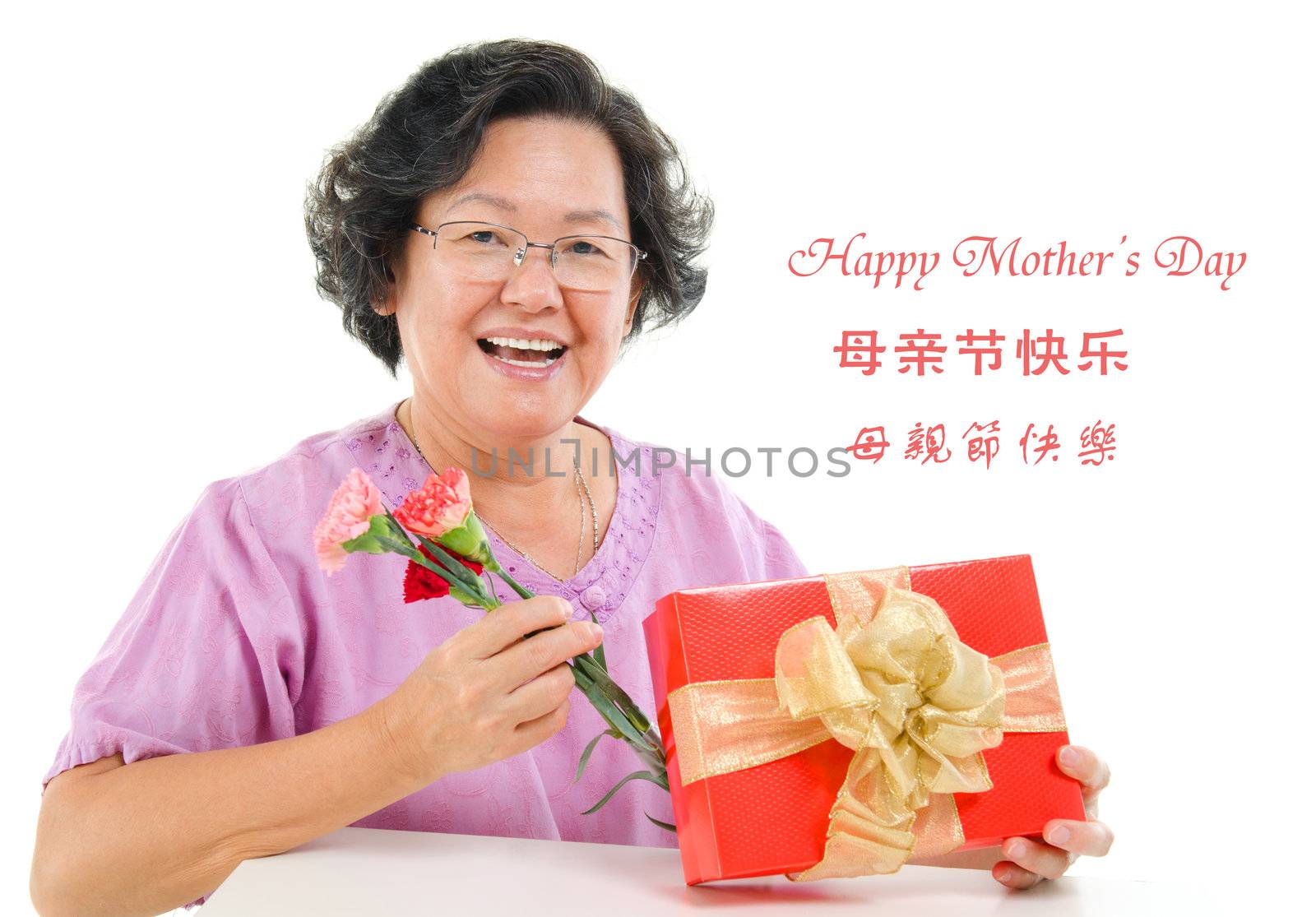 Happy mother's day concept. Asian senior mother showing a gift and carnation isolated on white background.