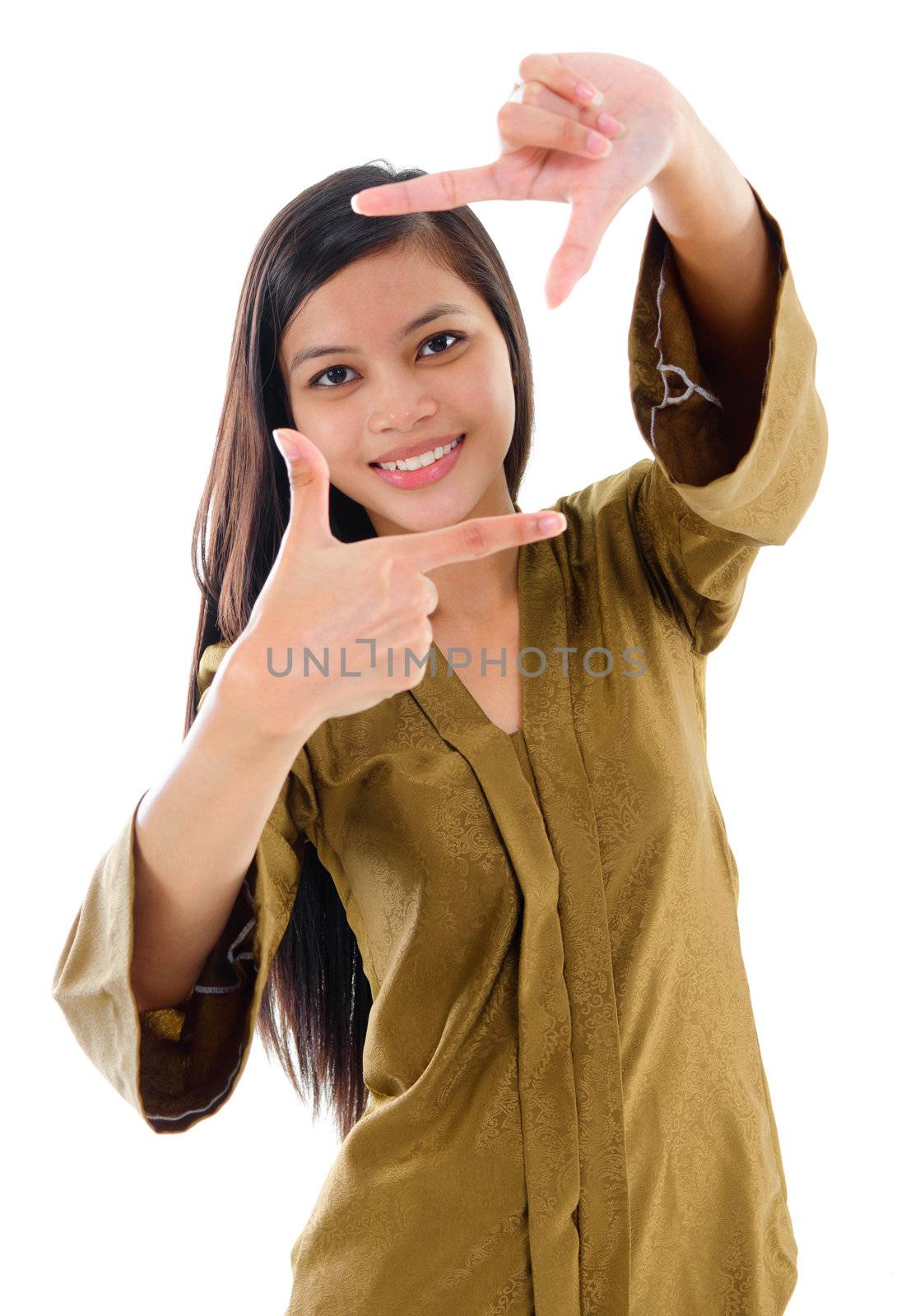 Smiling Southeast Asian Muslim female in traditional kebaya with long black hair making a frame by fingers standing isolated on white background.