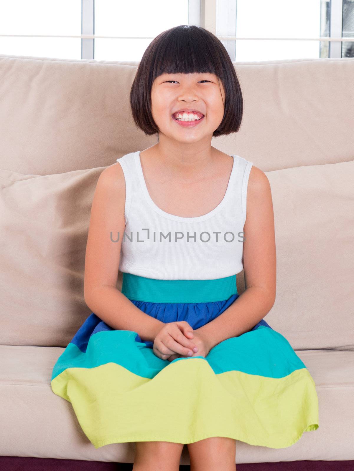 Seven years old Southeast Asian child sitting on sofa at home with happy face
