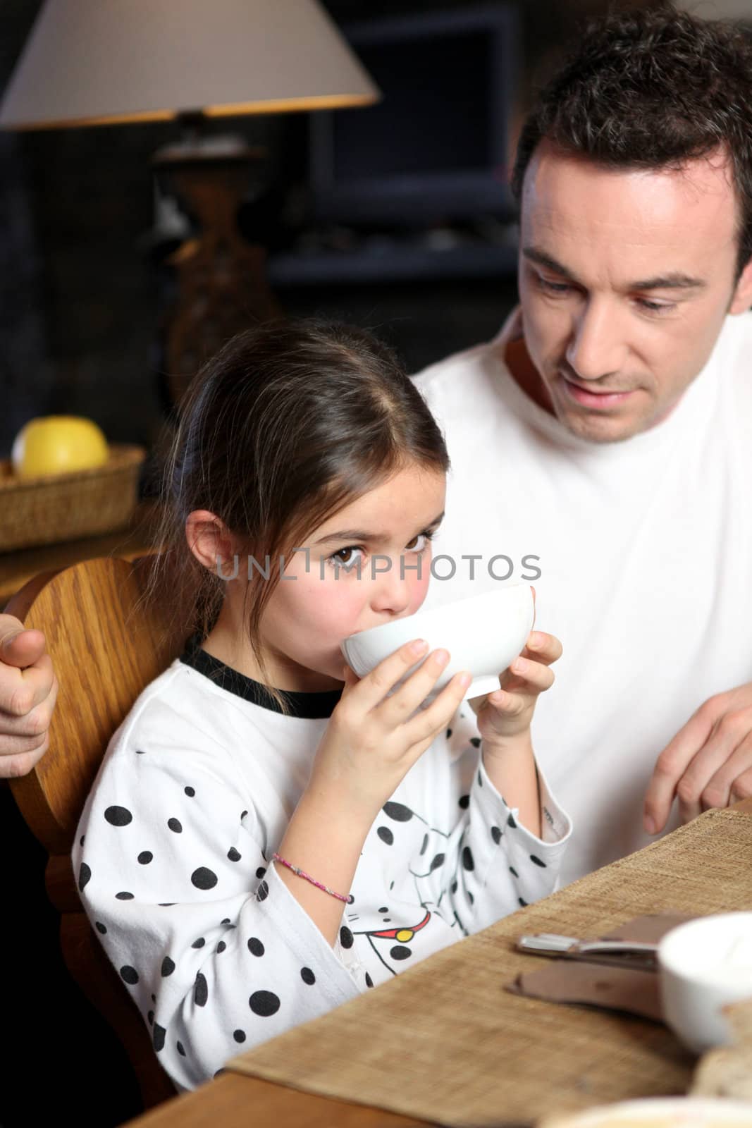 Man with little girl having breakfast by phovoir