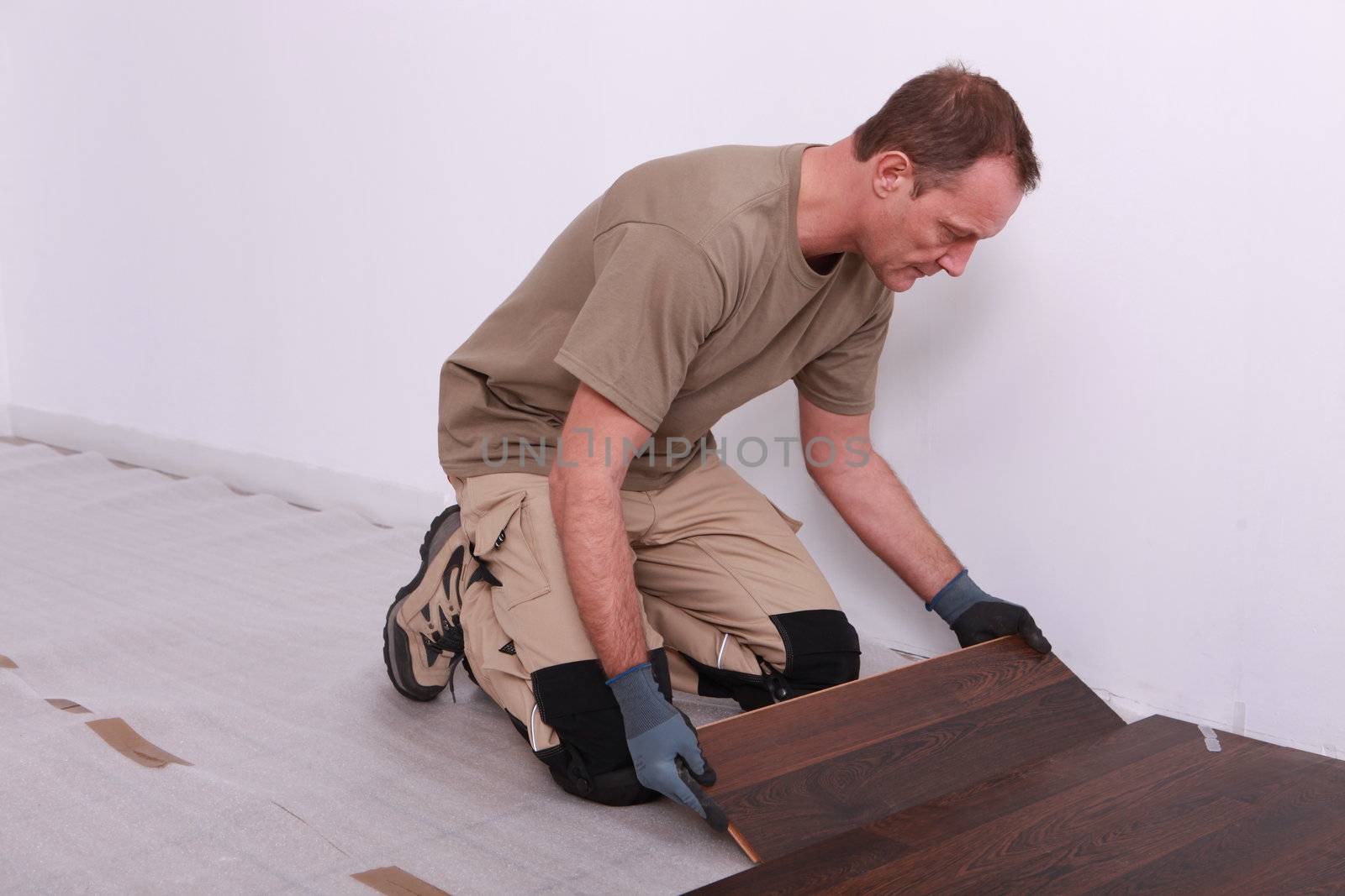Man laying laminate flooring by phovoir