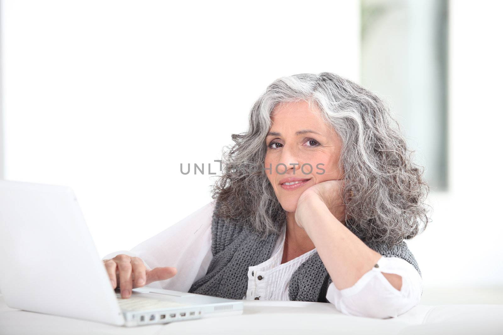 mature grey-haired lady with laptop by phovoir