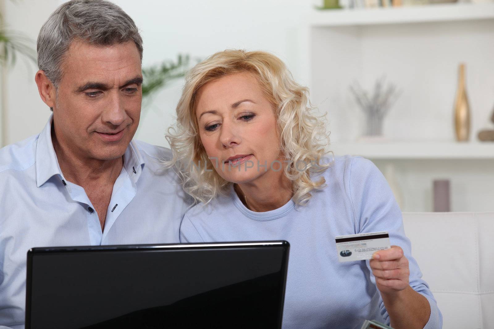 Older couple using a credit card online by phovoir
