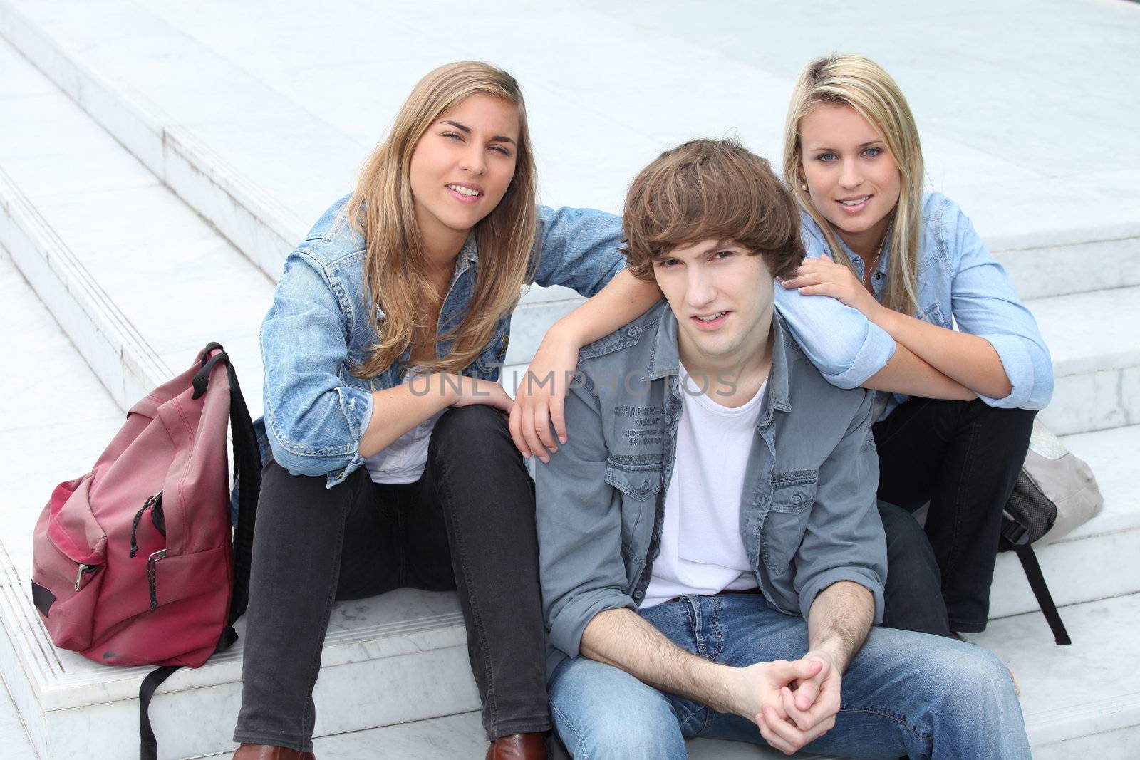 Three teenage friends sat on steps by phovoir