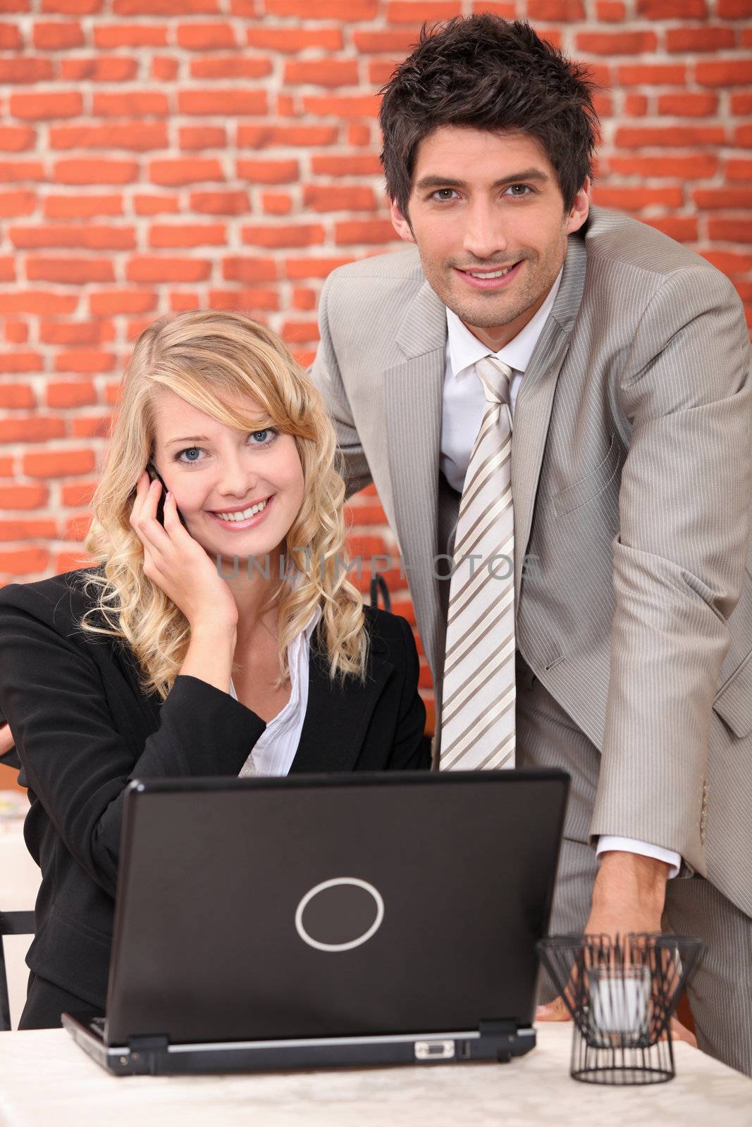 Smart couple with a laptop computer and cellphone by phovoir