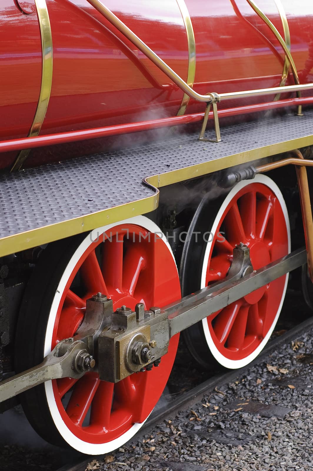 Vertical image of two red steam locomotive wheels