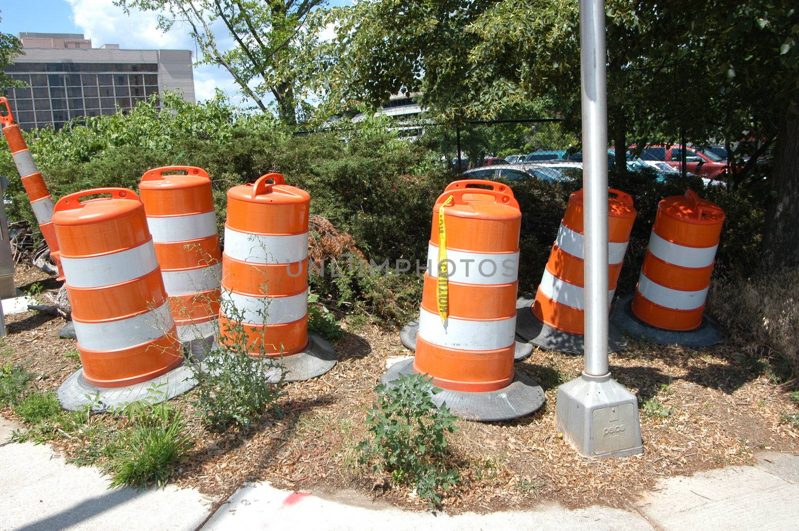 Orange and white traffic barrels ready for use in the city