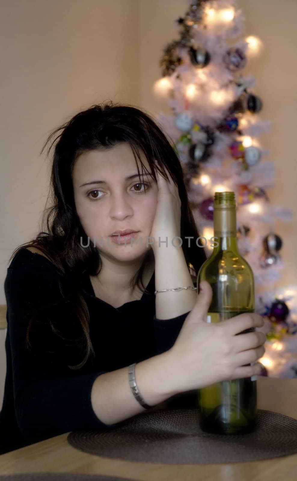 A depressed woman at christams holding a bottle of wine.