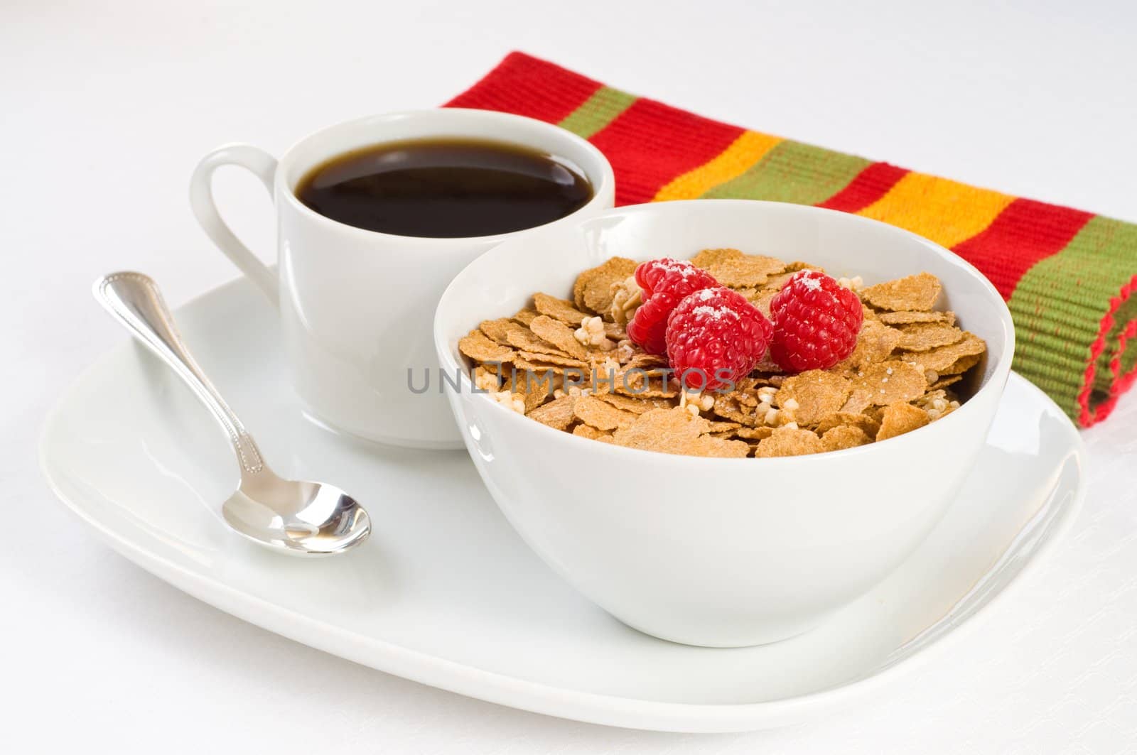 Bowl of cereal flakes and raspberries with coffee.